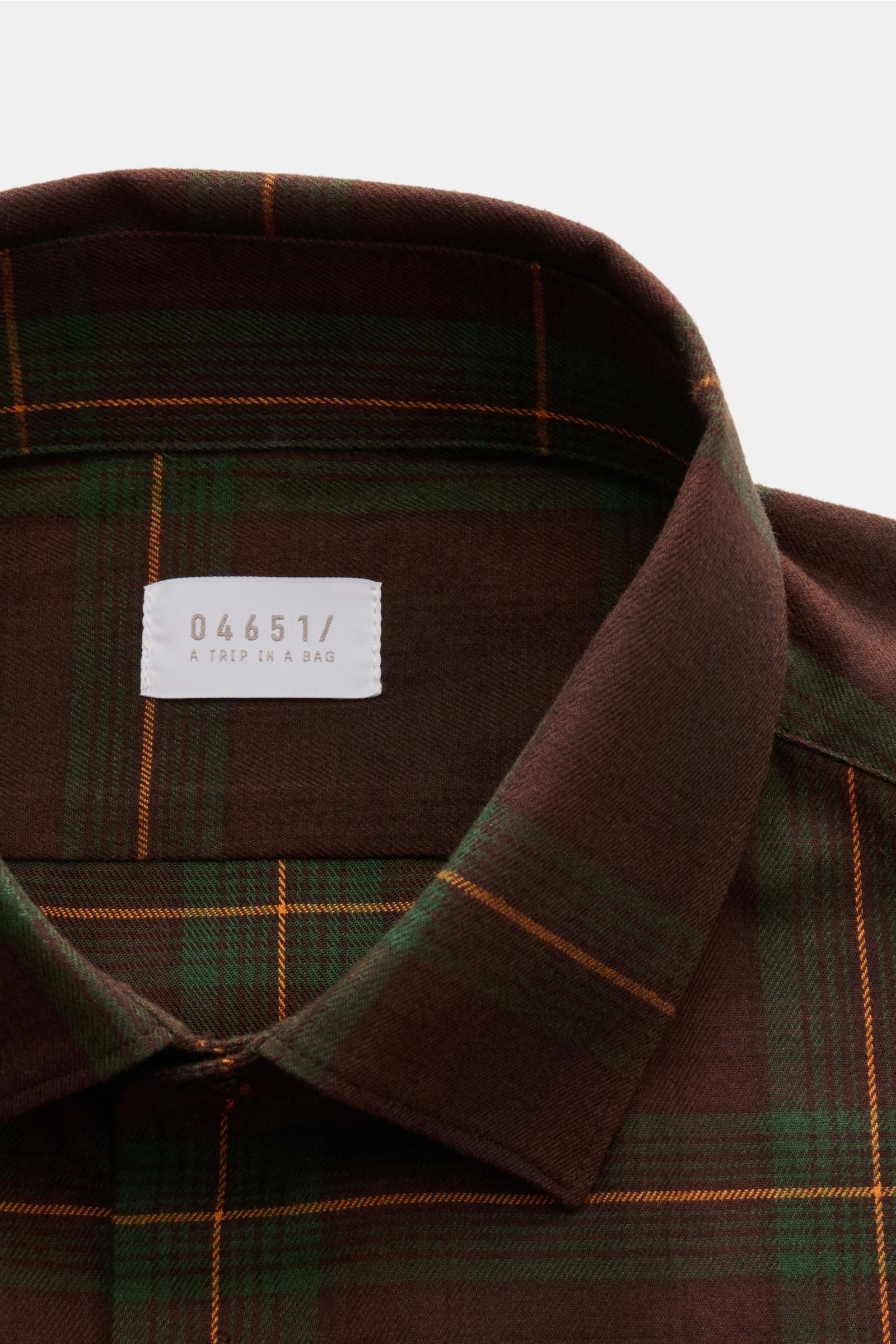 Close-up of the collar and label of the 04651/ A trip in a bag Flanellhemd Kent-Kragen braun/dunkelgrün/bordeaux kariert, showing the classic Kent collar and fine cotton twill fabric from a top-front perspective. Dieses lässig geschnittene Flanellhemd 