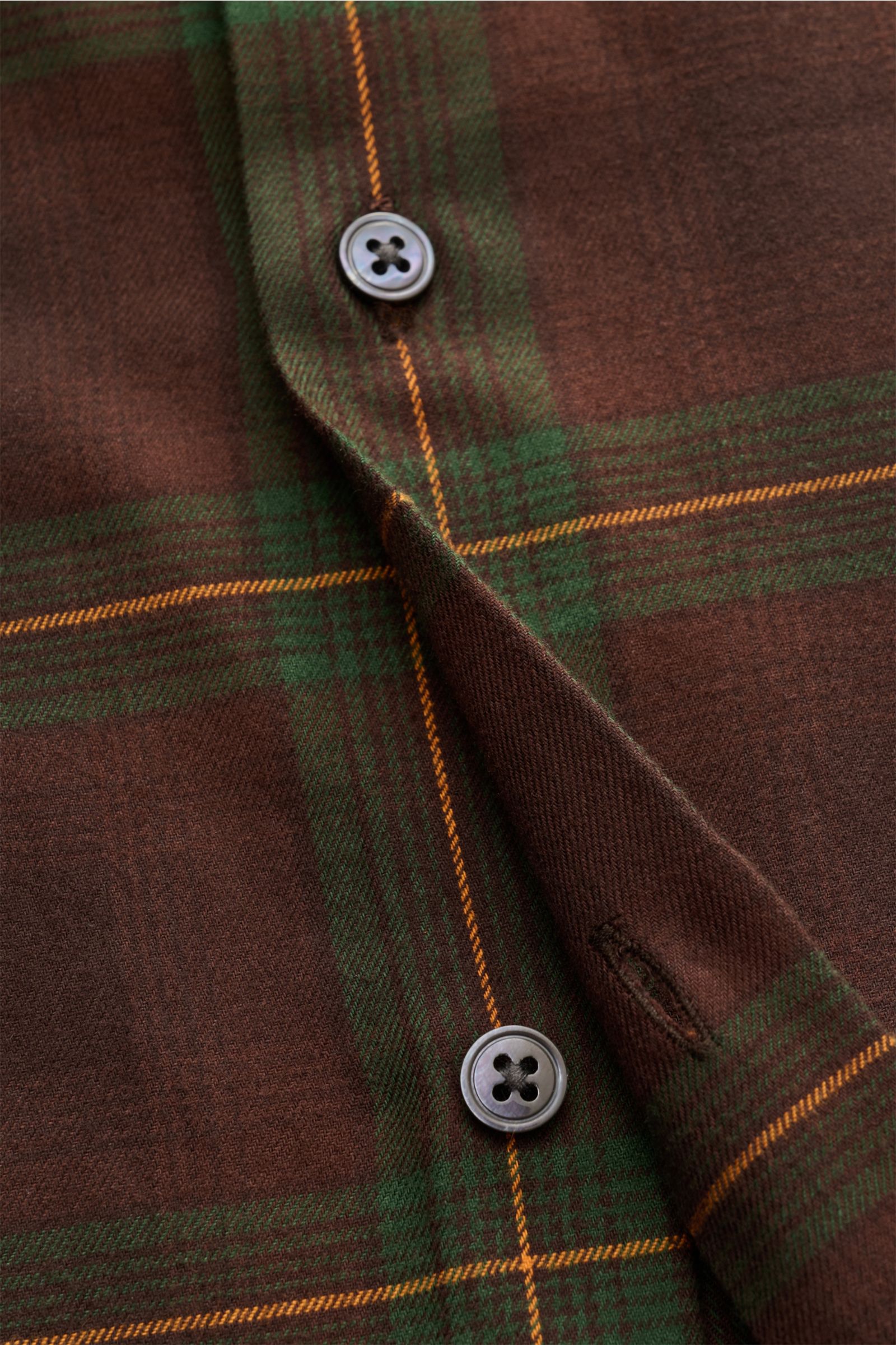 Close-up front view of the 04651/ A trip in a bag Flanellhemd Kent-Kragen braun/dunkelgrün/bordeaux kariert, showing button details and fabric texture. Dieses lässig geschnittene Flanellhemd mit klassischem Kent-Kragen von 04651/ A TRIP IN A BAG wurde 