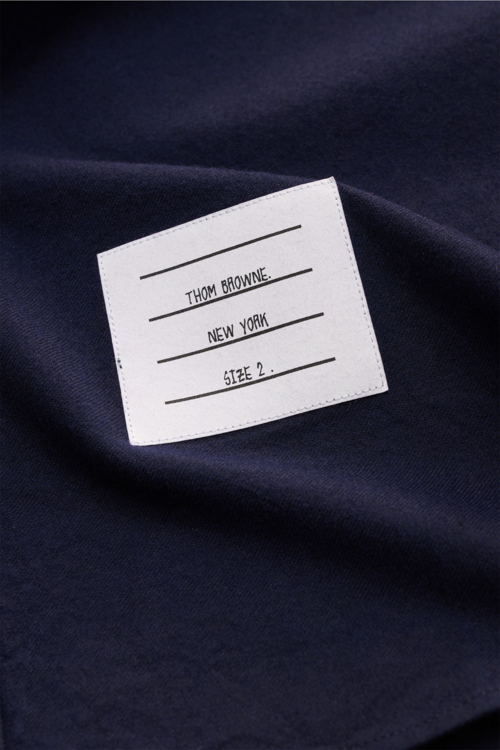 Nahaufnahme des navyfarbenen Thom Browne Flanellhemd Button-Down-Kragen mit weichem Griff und sichtbarem Markenlabel, Detailansicht.