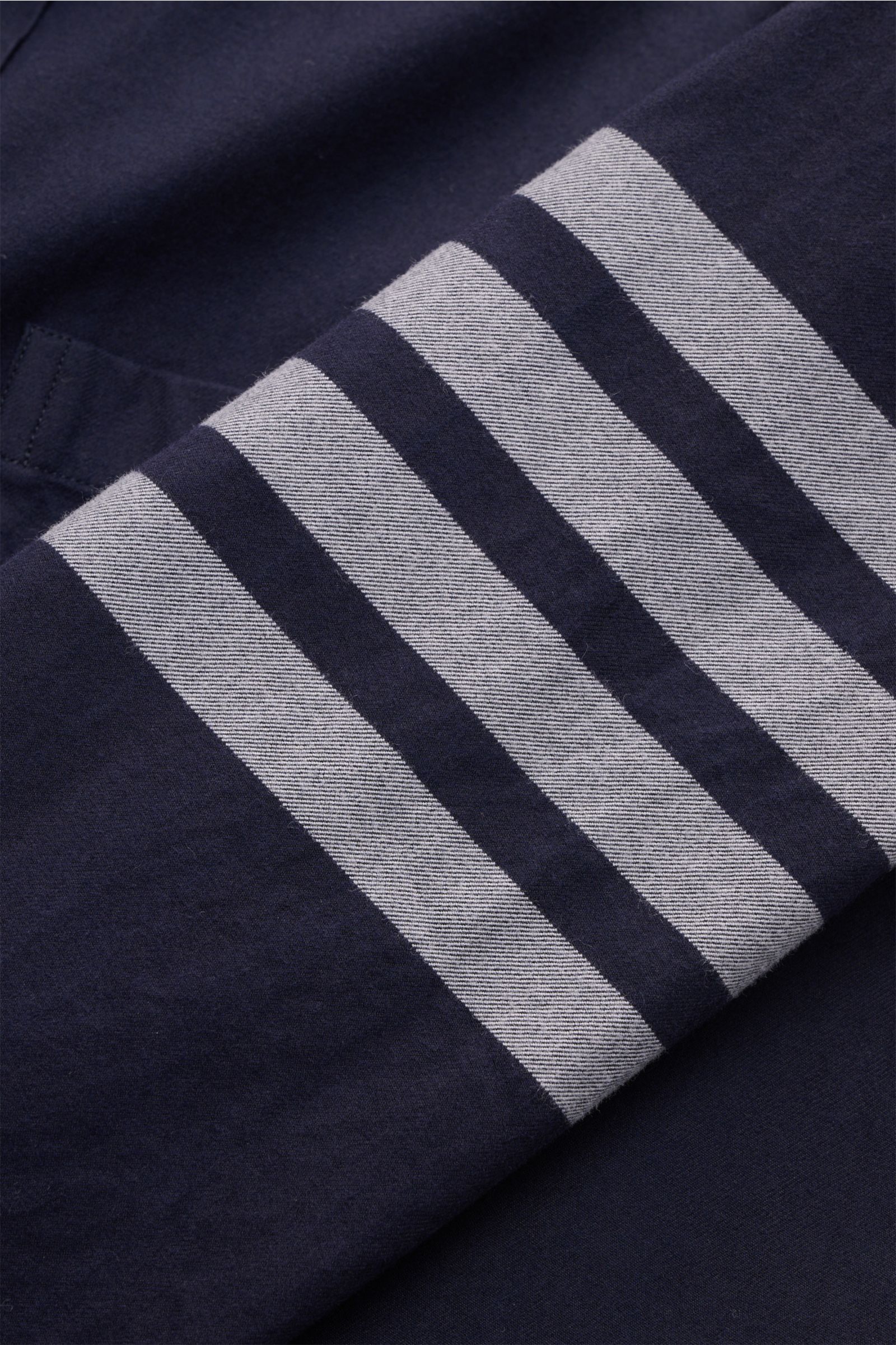 Nahaufnahme des Ärmels vom Thom Browne Flanellhemd Button-Down-Kragen navy in Navyblau mit weichem Griff und markanten grauen Streifen.