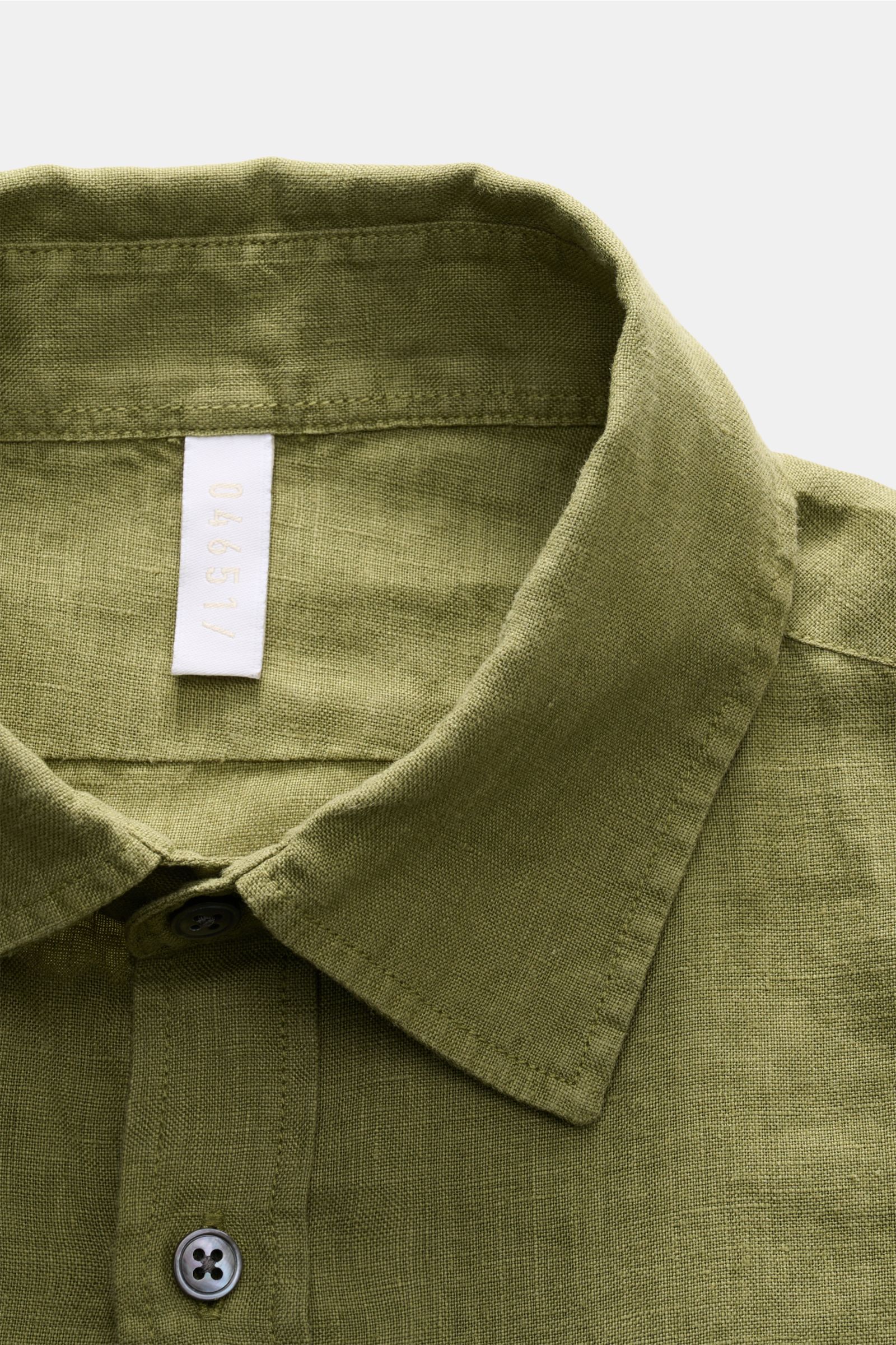 Close-up front view of the olive green 04651/ A trip in a bag Leinenhemd Kent-Kragen oliv shirt collar and top buttons, showing fine linen texture. Mühelose Leichtigkeit