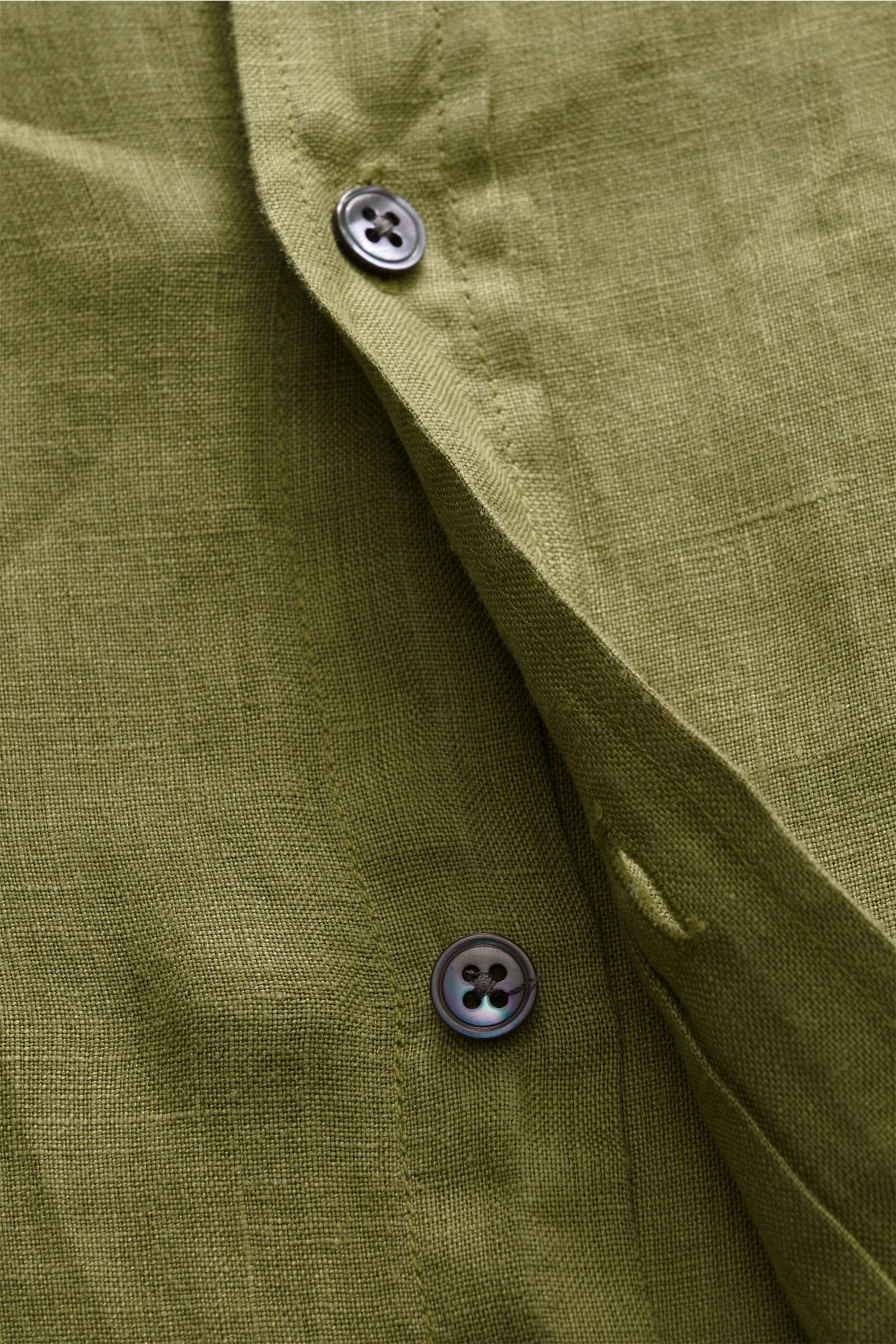 Close-up view of olive green 04651/ A trip in a bag Leinenhemd Kent-Kragen oliv showing linen texture and button details, highlighting mühelose Leichtigkeit: Dieses Hemd aus reinem Leinen von 04651/ A TRIP IN A BAG überzeugt mit luftigem Tragegefühl und e