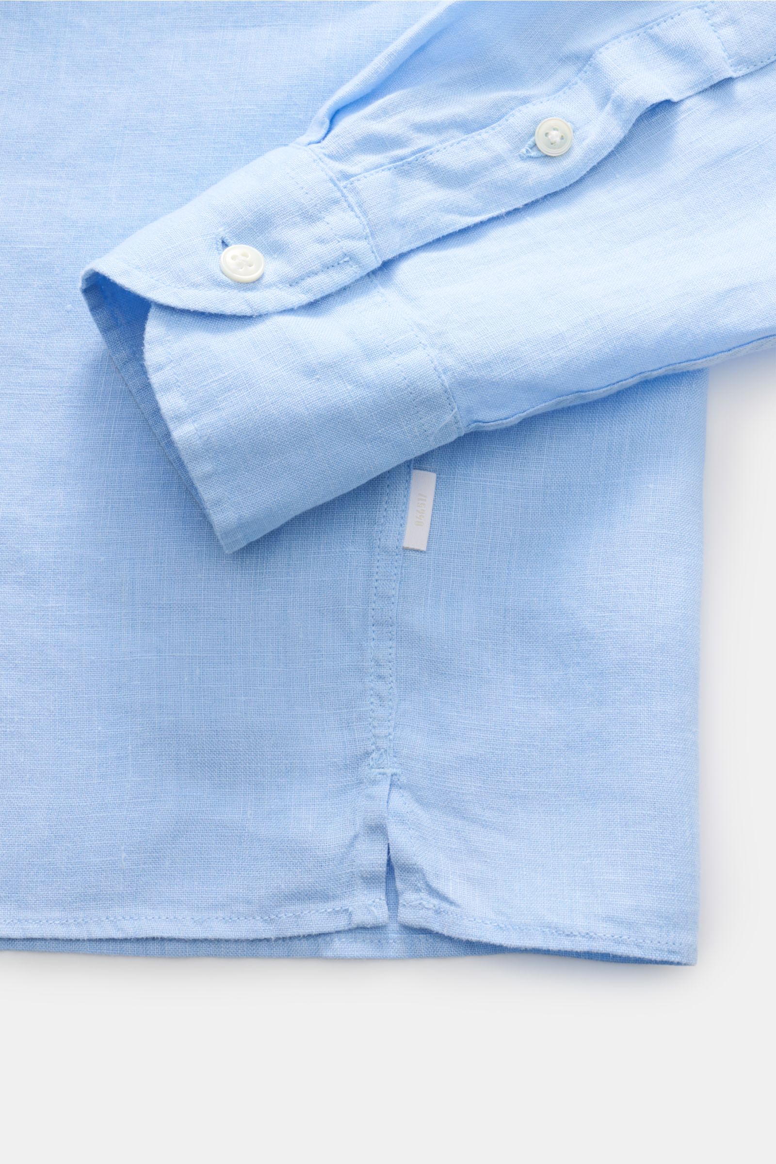 Close-up view of the cuff and side hem with small web label of the light blue 04651/ A trip in a bag Leinenhemd Kent-Kragen hellblau, made of pure linen with airy texture, regular fit, Kent collar, button placket, sport cuff, rounded hem, back waist darts