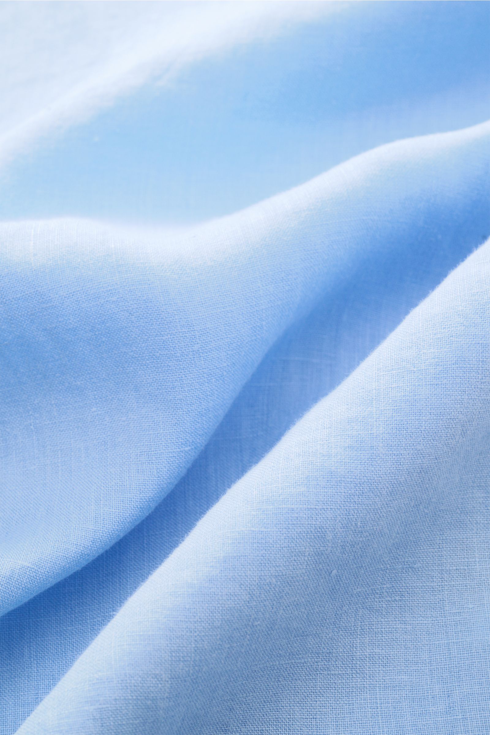 Close-up view of light blue linen fabric with visible texture and weave, highlighting the airy quality of the 04651/ A trip in a bag Leinenhemd Kent-Kragen hellblau. Mühelose Leichtigke
