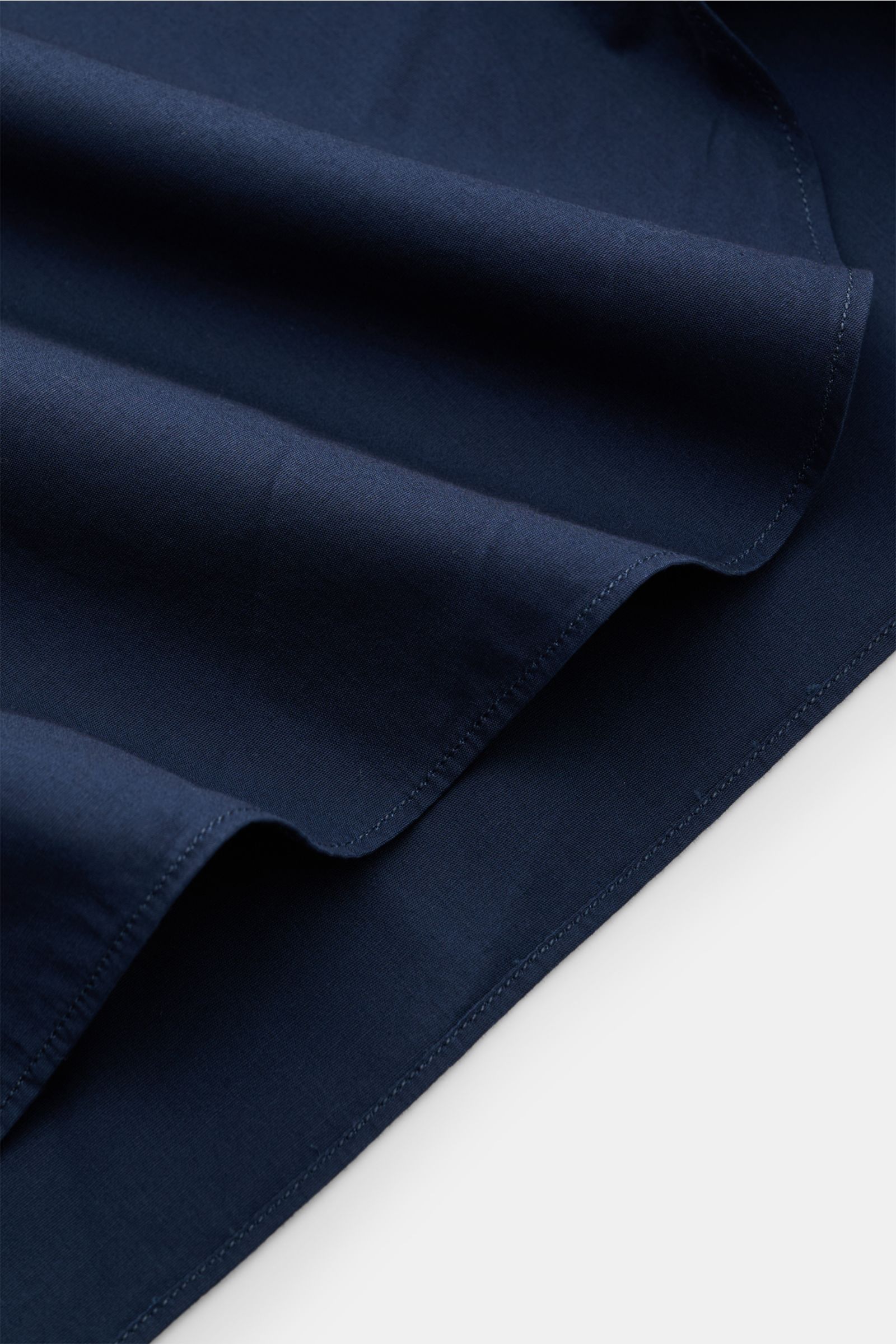 Close-up of the navy fabric hem of the Borrelli Casual Hemd Haifisch-Kragen navy, photographed from a top diagonal angle, showing soft pure cotton poplin with a rounded hem.

Description: Stilvoller Klassiker für Büro und Freizeit: Das Popeline-Hemd vo
