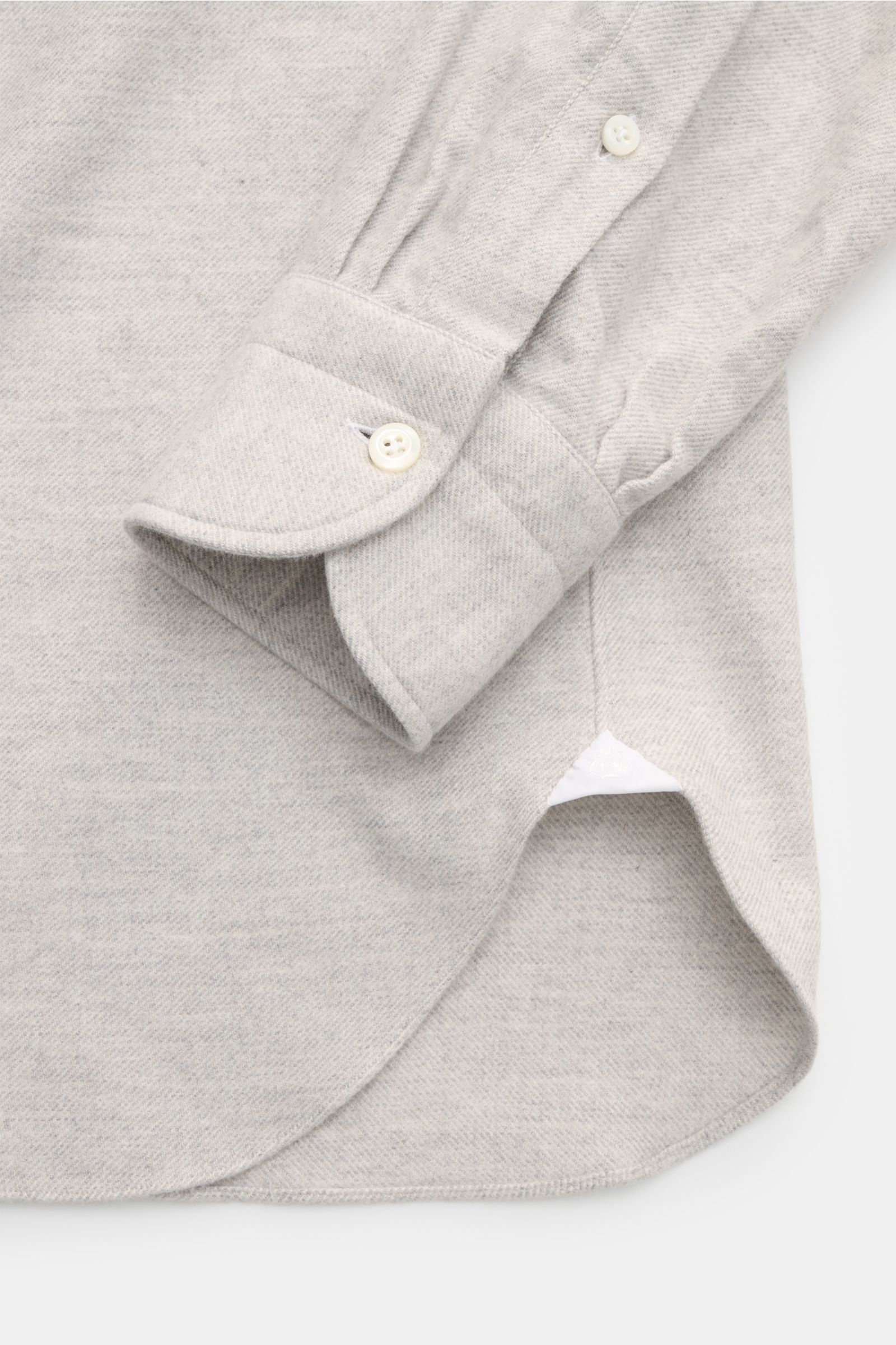 Close-up view of the cuff and hem of the Giampaolo Flanellhemd Haifisch-Kragen hellgrau meliert, showing soft, heathered light grey cotton twill fabric with a classic sport cuff and rounded hem.

Alltagstauglicher Klassiker: Das edle Flanellhemd des it