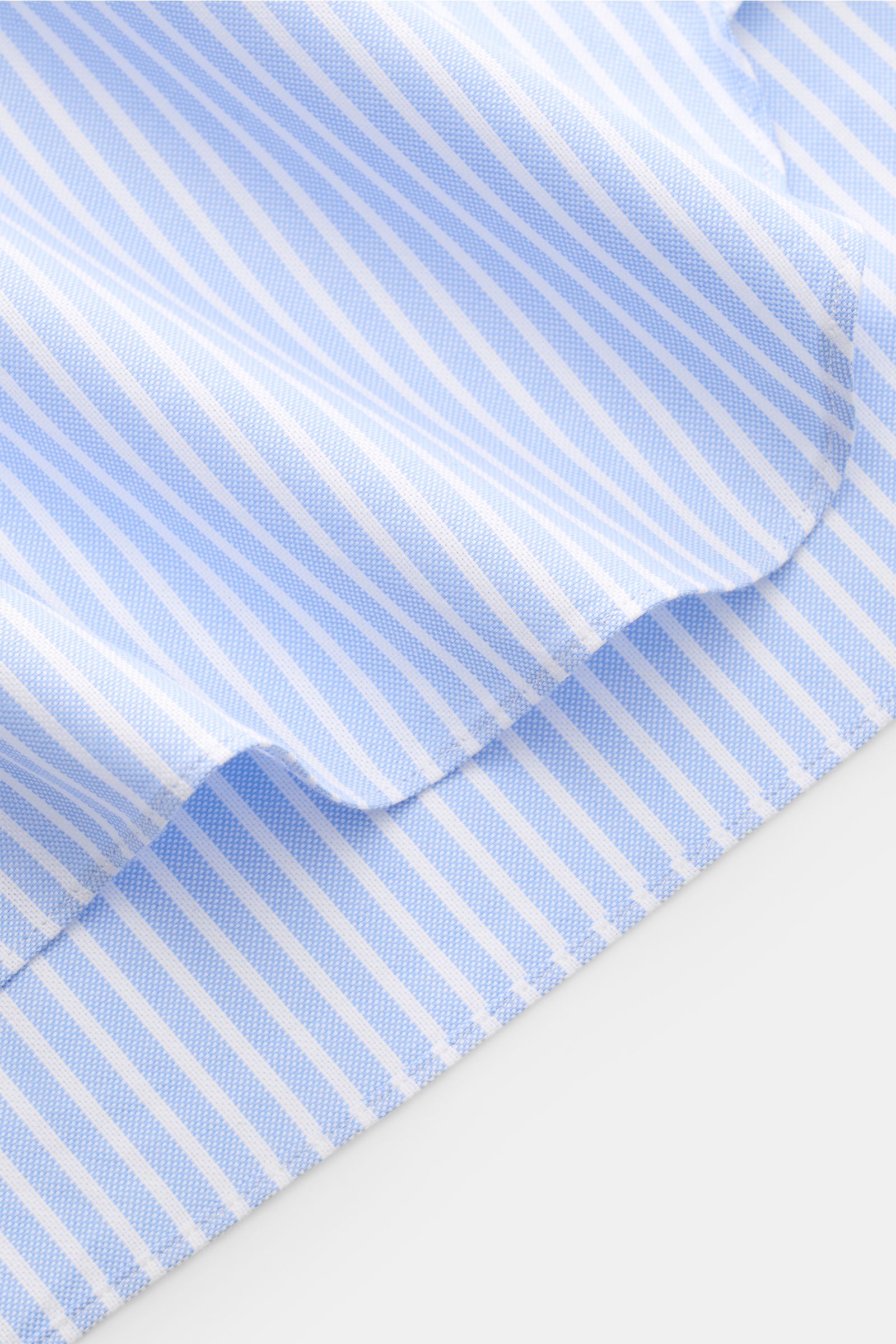 Close-up view of the hem of the Giampaolo Oxford-Hemd Haifisch-Kragen hellblau/weiß gestreift, showing light blue and white stripes with Oxford fabric texture. Oxford aus reiner Baumwolle, weicher, leicht strukturierter Griff, Slim Fit, Haifisch-Kragen, f