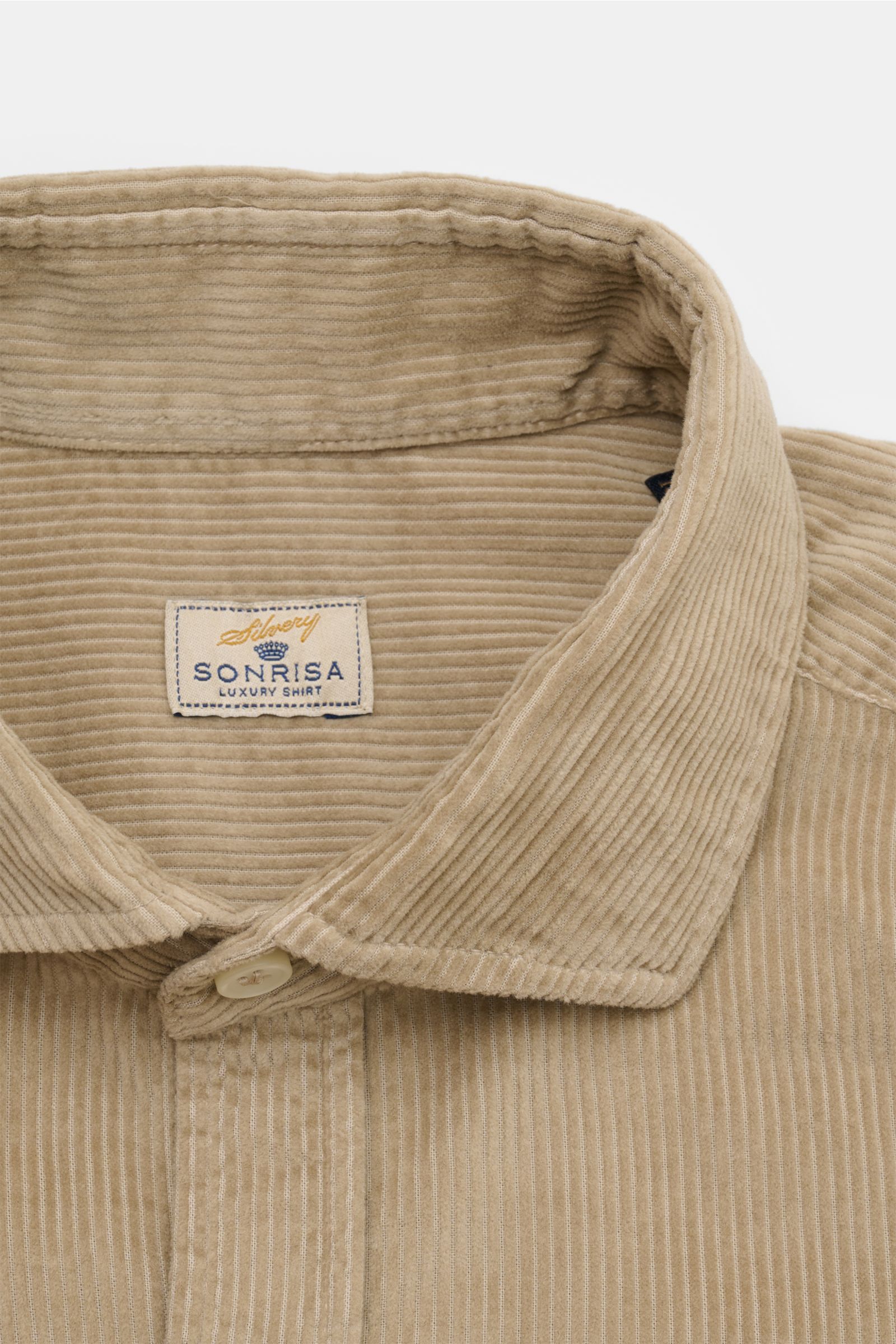 Nahaufnahme aus schräger Draufsicht des Sonrisa Cordhemd Haifisch-Kragen taupe aus weichem Baumwollcord mit Knopfleiste und Label.