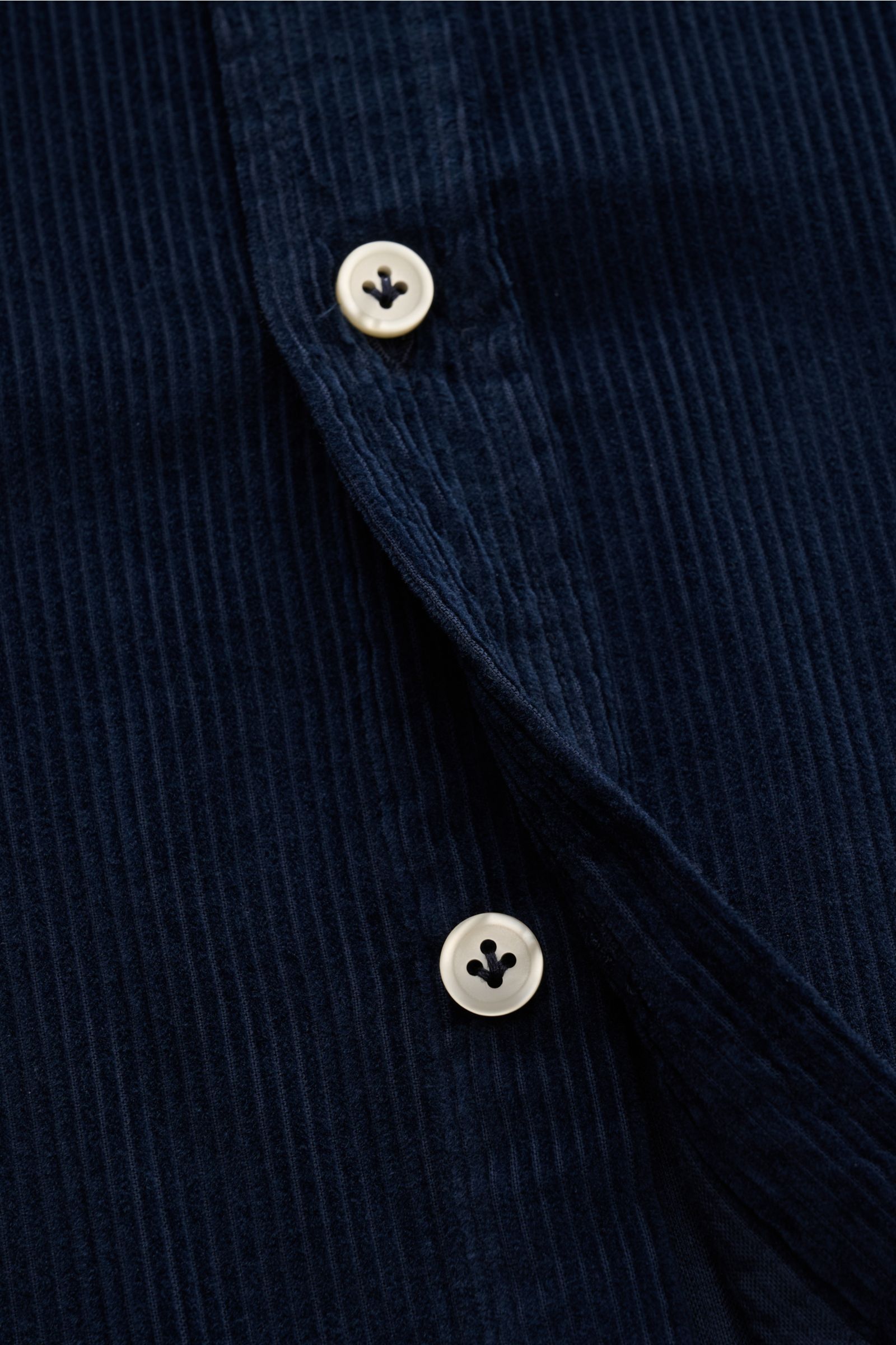 Nahaufnahme eines navyfarbenen Sonrisa Cordhemd Haifisch-Kragen navy aus Baumwollcord mit weißer Knopfleiste, weichem Griff und gerundetem Saum.