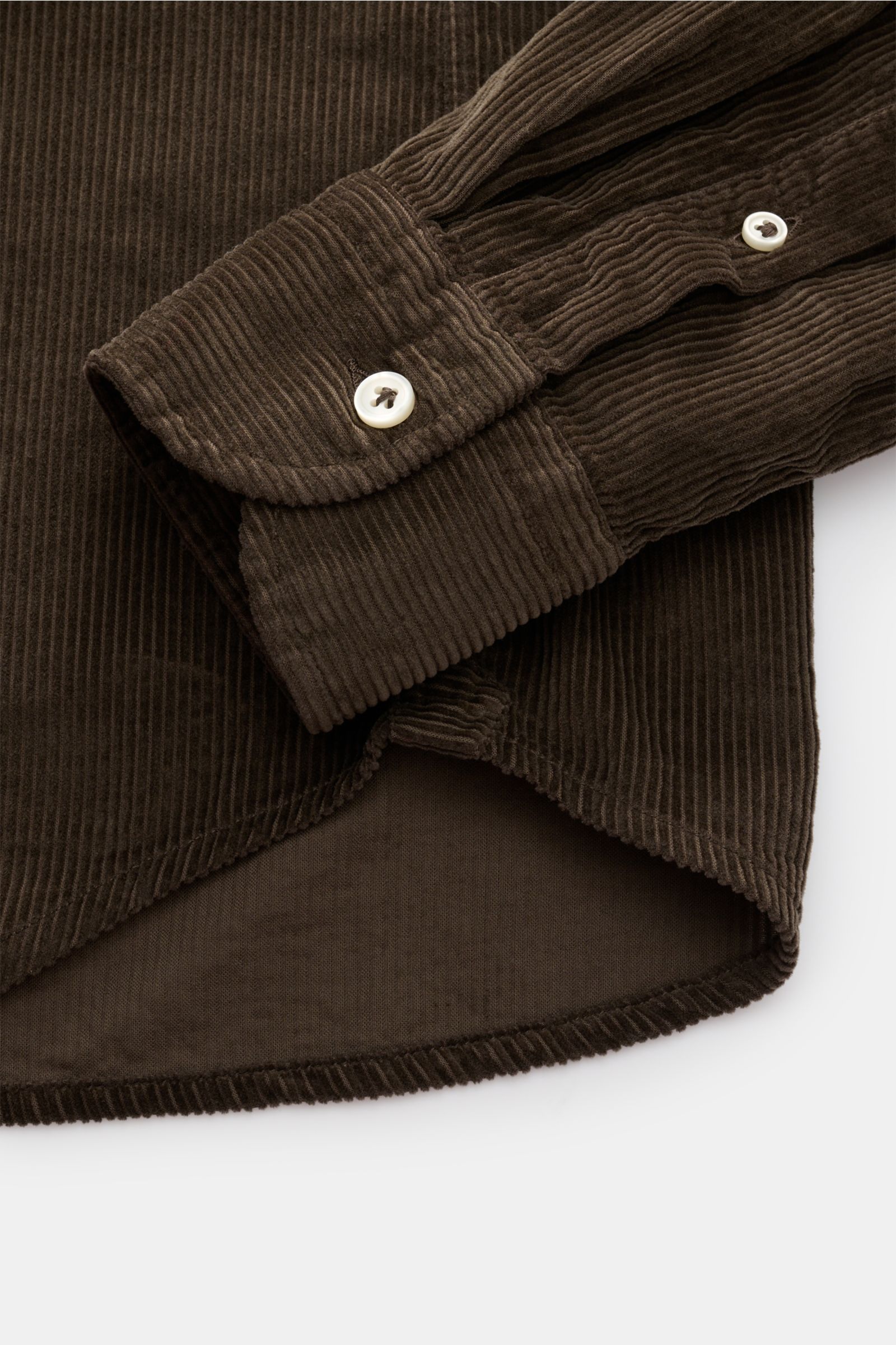 Detailaufnahme von Saum und Manschette des Sonrisa Cordhemd Haifisch-Kragen khaki aus weichem Baumwollcord, Slim Fit, Haifisch-Kragen, klassischer Sportmanschette, leicht gerundetem Saum und kleinem Weblabel.