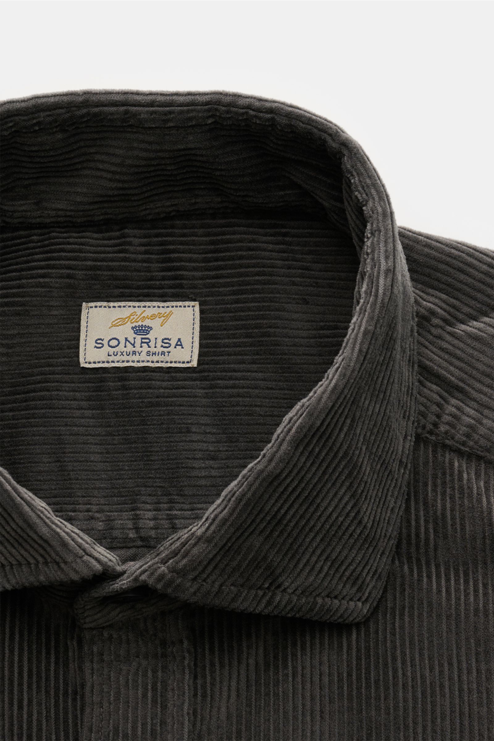 Nahaufnahme des Sonrisa Cordhemd Haifisch-Kragen dunkelgrau aus Baumwollcord mit weichem Griff, Slim Fit, klassischer Sportmanschette, aufgesetzter Knopfleiste und kleinem Weblabel, fotografiert von vorne oben.