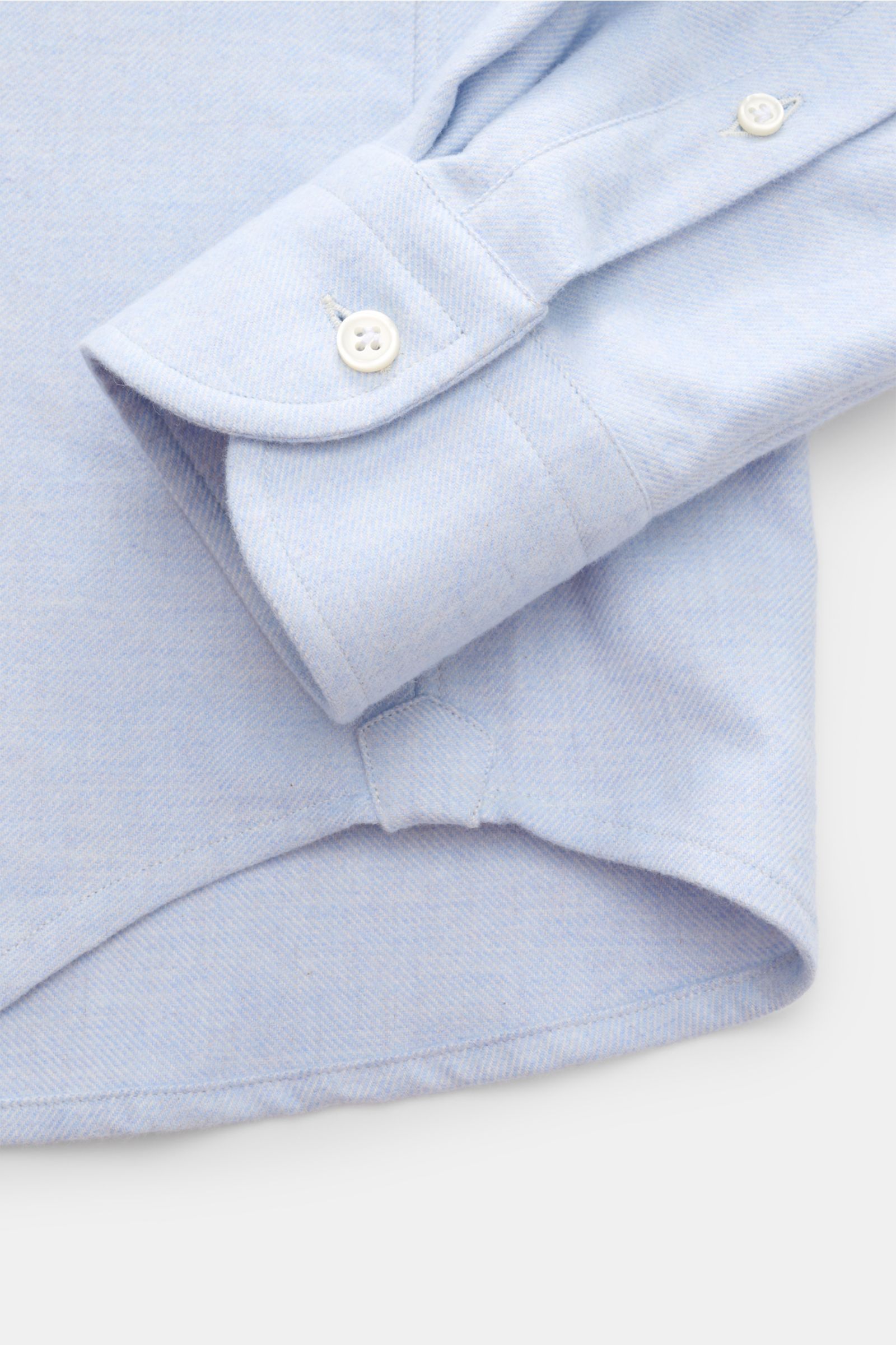 Nahaufnahme vom Saum und klassischer Sportmanschette des Sonrisa Flanellhemds Haifisch-Kragen hellblau meliert aus reiner Baumwolle, Slim Fit, weicher Griff, mit französischer Knopfleiste und kleinem Weblabel.