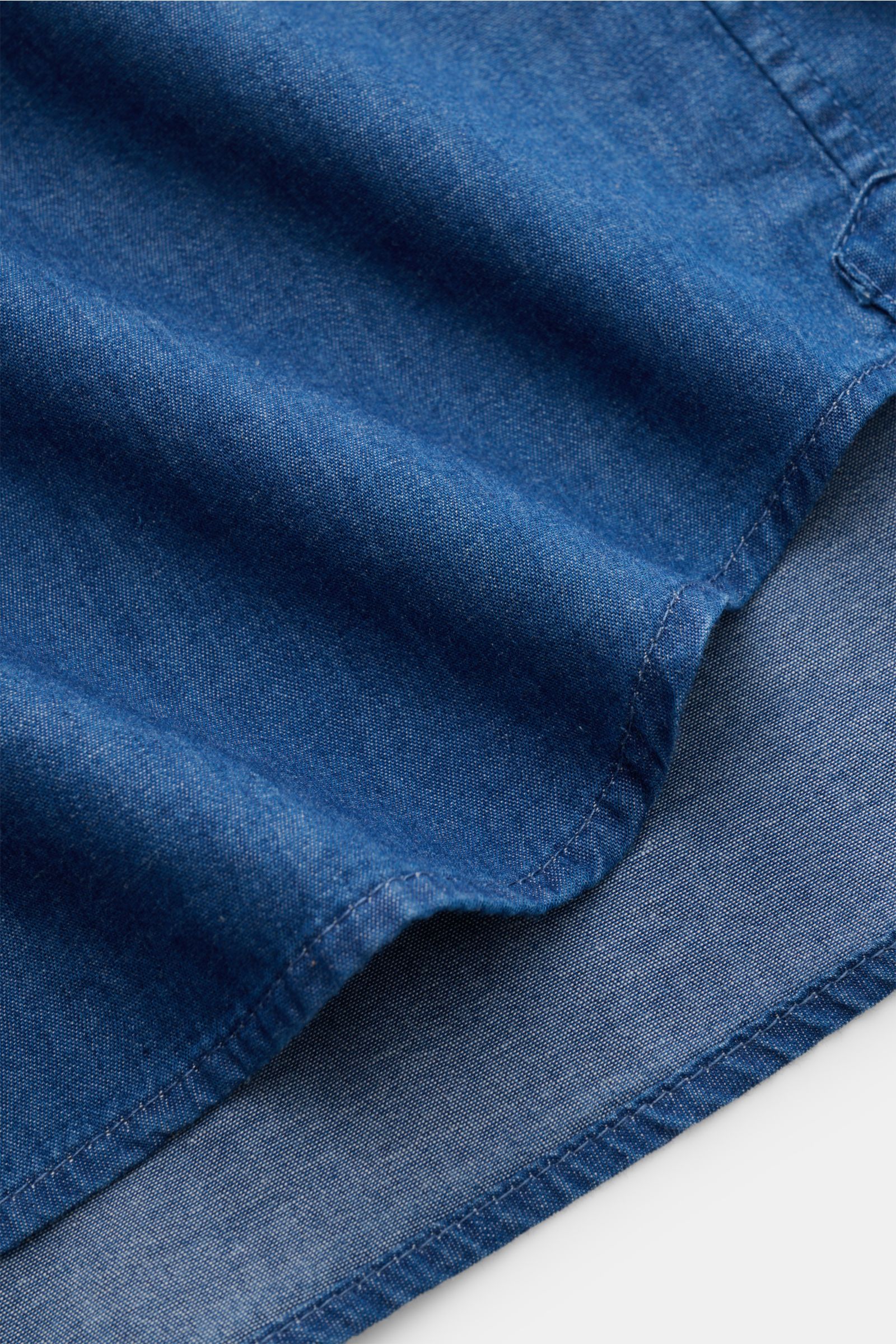 Nahaufnahme des leicht gerundeten Saumverlaufs vom Sonrisa Chambray-Hemd Haifisch-Kragen blau aus reiner Baumwolle, Slim Fit und weichem Griff.