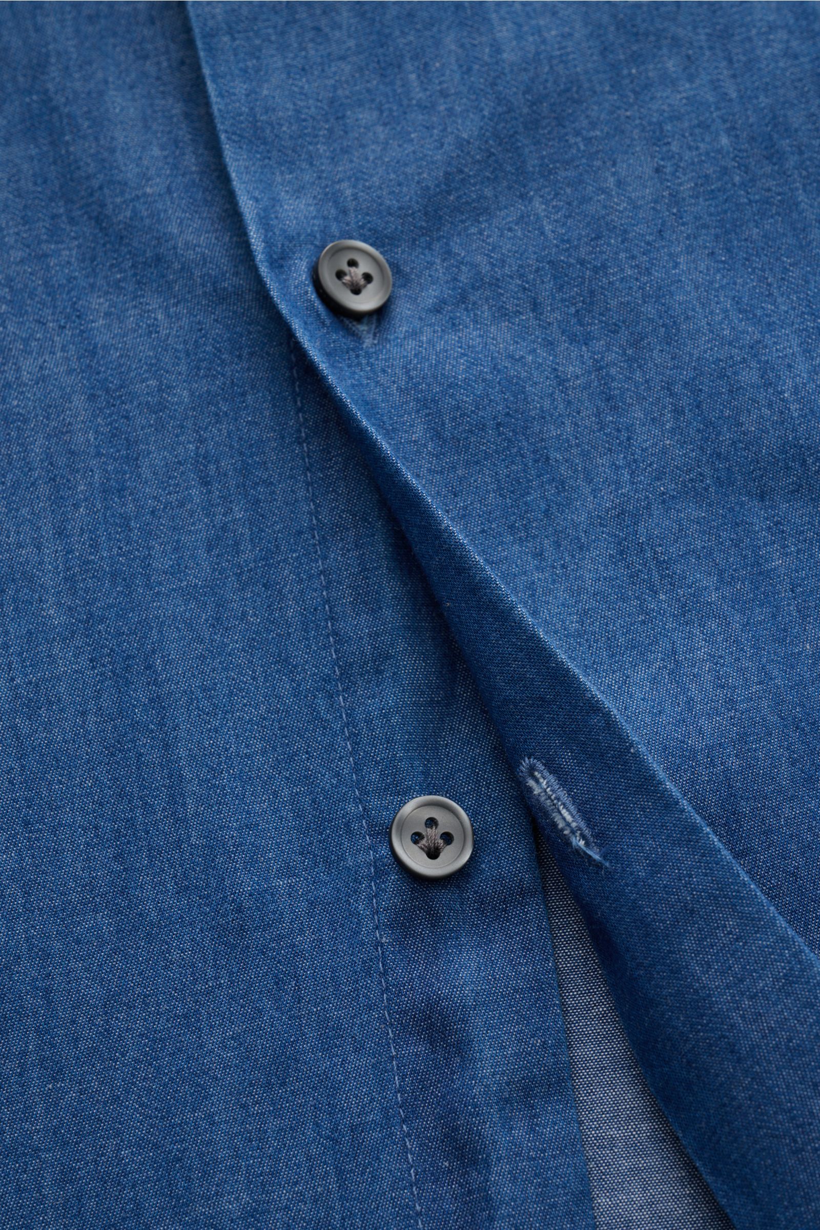 Nahaufnahme aus schräger Perspektive eines blauen Sonrisa Chambray-Hemd Haifisch-Kragen blau mit französischer Knopfleiste, Slim Fit und weichem Griff.