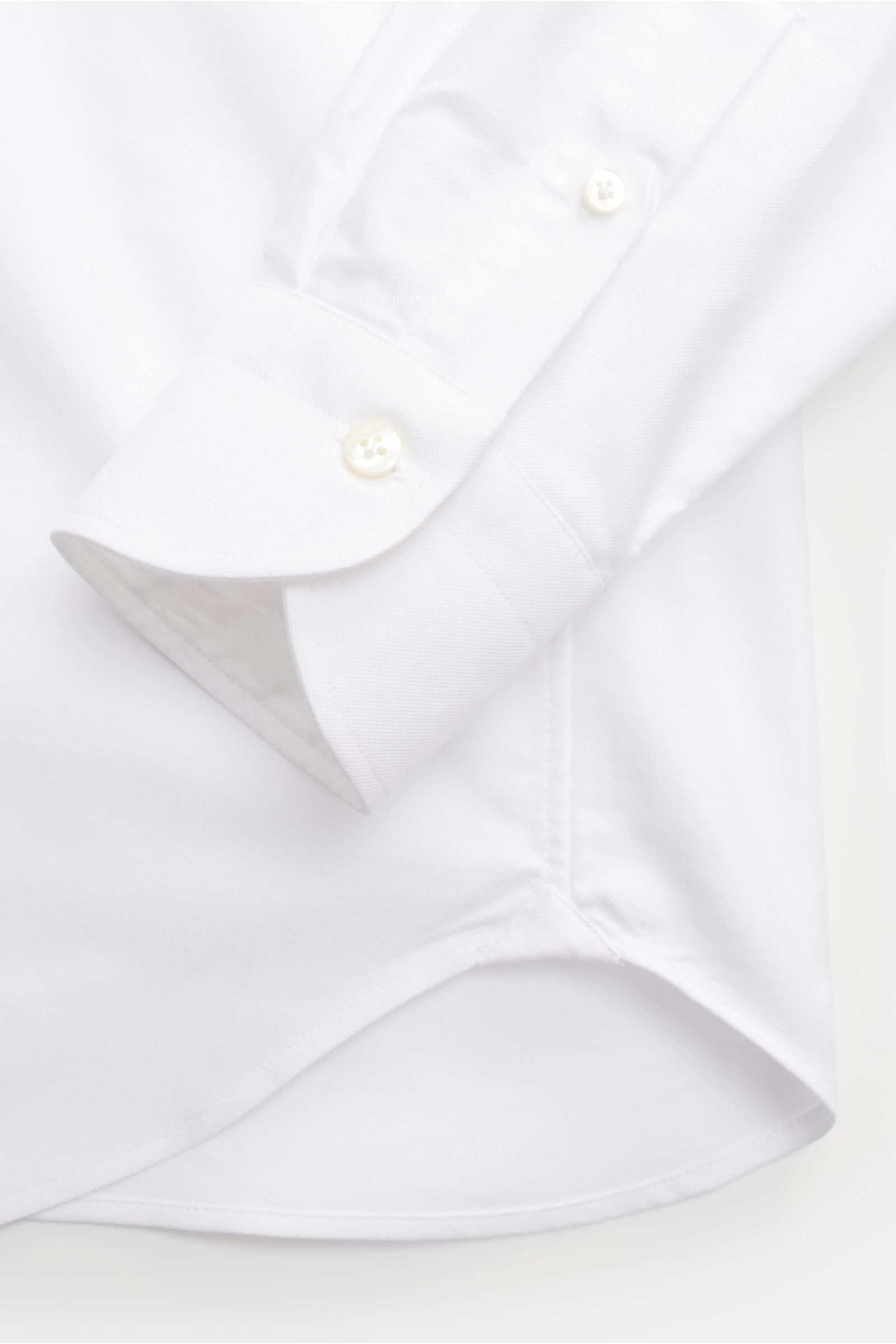 Nahaufnahme des gerundeten Saumverlaufs und der klassischen Sportmanschette des Guglielminotti Oxford-Hemd Haifisch-Kragen weiß, Oxford aus reiner Baumwolle, glatter Griff, Slim Fit mit rückwärtigen Taillenabnähern, französische Knopfleiste mit Perlmuttkn
