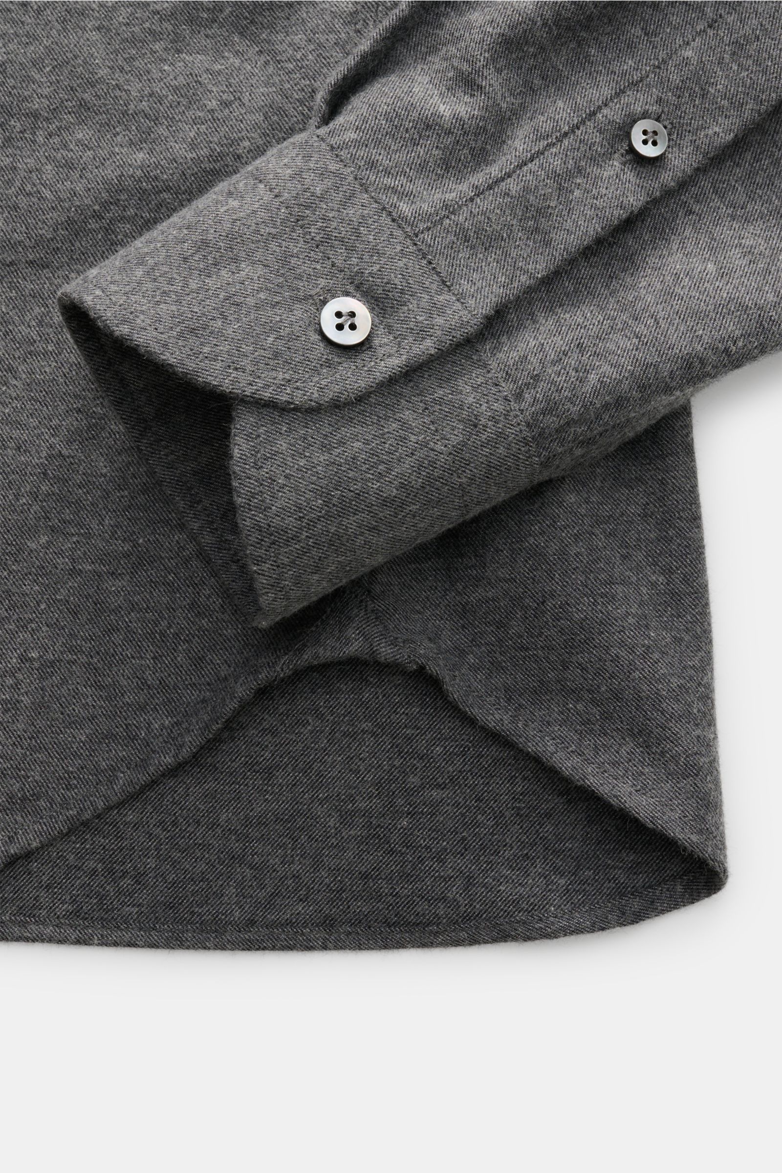 Close-up image of the Guglielminotti Flannel shirt shark collar dark grey melange, showing the cuff and rounded hem from a top-down angle. Cotton and cashmere flannel, soft feel, regular fit, shark collar, French button placket, classic barrel cuffs, wais