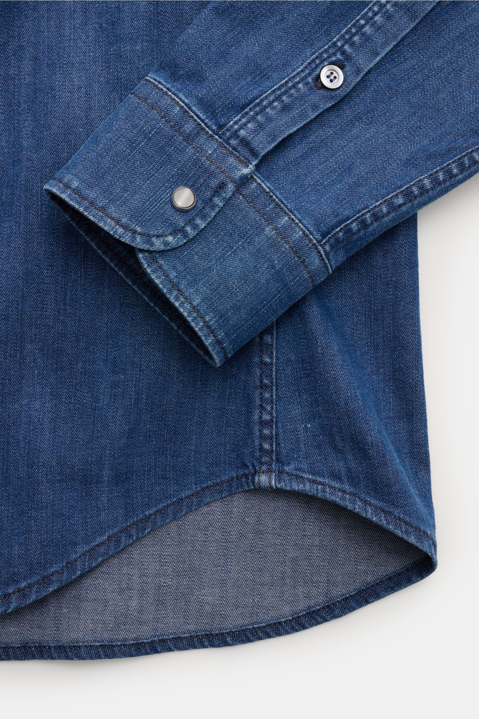 Close-up view of the cuff and hem of Dondup Jeanshemd 'Camicia' Kent-Kragen blau, a slim fit denim shirt with elastic cotton, soft touch, Western-style yoke, and rounded hem. Modern denim statement with Kent collar, button placket, chest pockets with flap