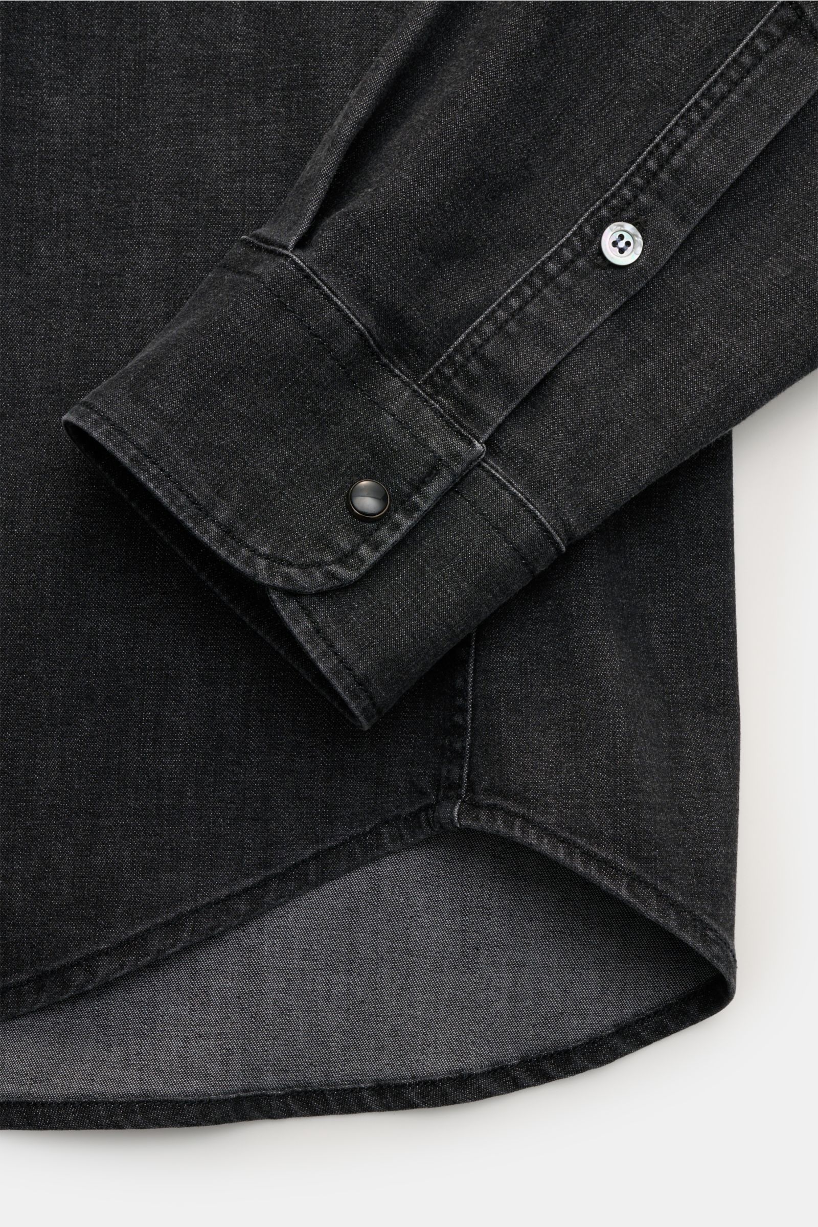 Close-up side view of the sleeve cuff and curved hem of the Dondup Jeanshemd 'Camicia' Kent-Kragen dunkelgrau, a slim fit dark grey denim shirt.

Modernes Denim Statement: Das Jeanshemd von DONDUP präsentiert einen Klassiker in edler, moderner Ausführu