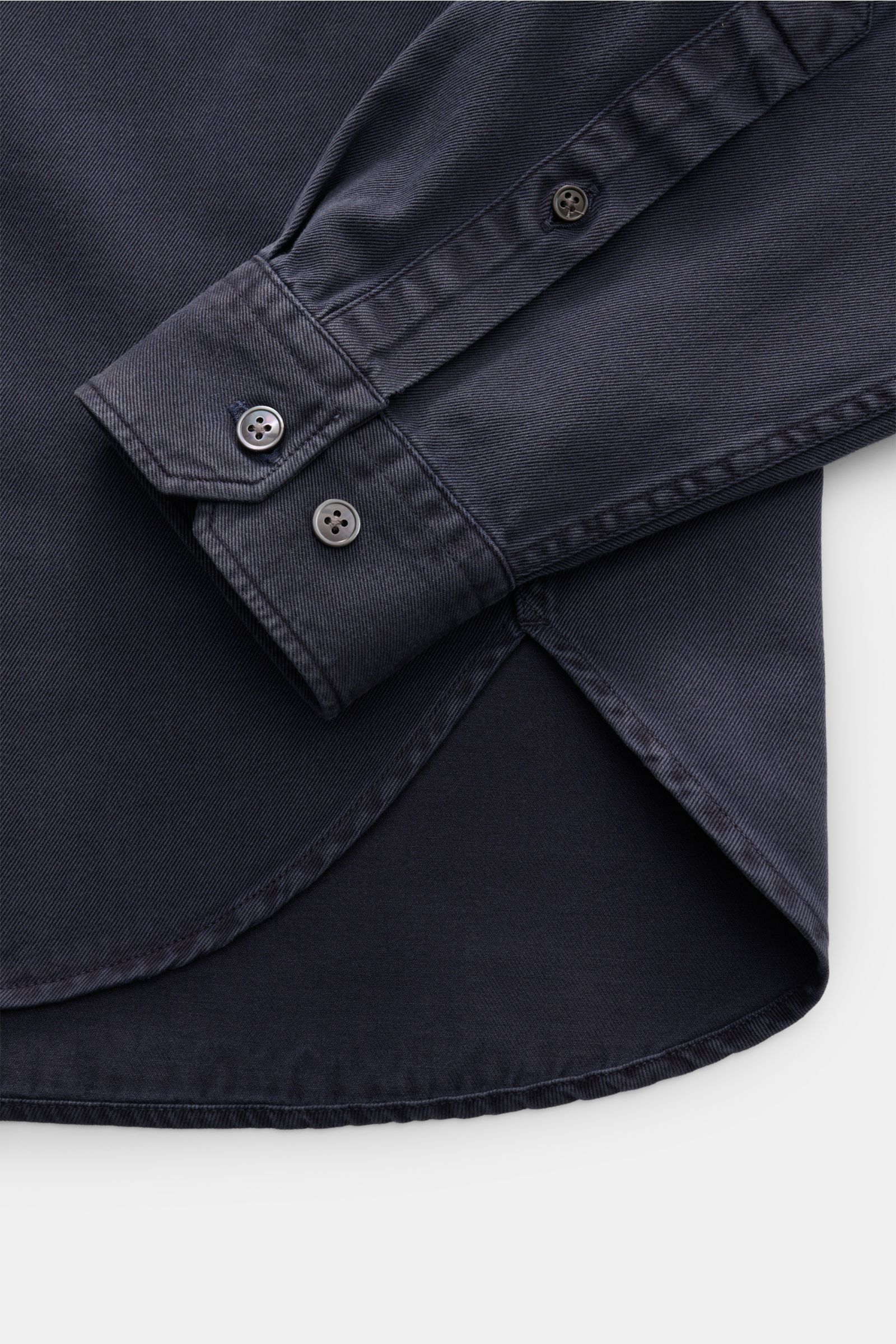 Nahaufnahme des anthrazitfarbenen Closed Jeanshemds mit schmalem Kragen, gerundetem Saum und Perlmuttknöpfen an Manschette, fotografiert von oben.