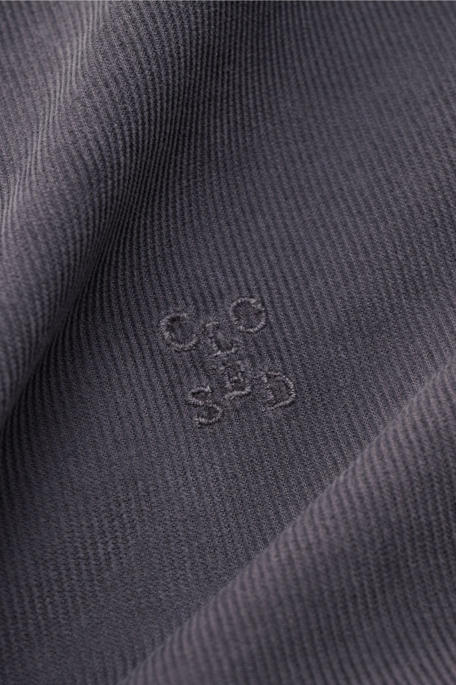 Close-up of the dark grey closed cordhemd button-down-kragen showing fine cord fabric texture and tonal CLOSED stitching from a front angle.