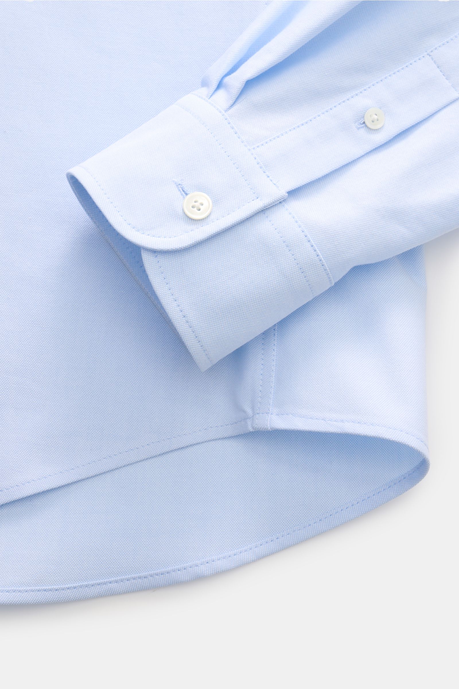 Nahaufnahme des hellblauen Ami Paris Oxford-Hemds Button-Down-Kragen, Oversized Fit, mit klassischer Sportmanschette und gerundetem Saum, fotografiert von oben.