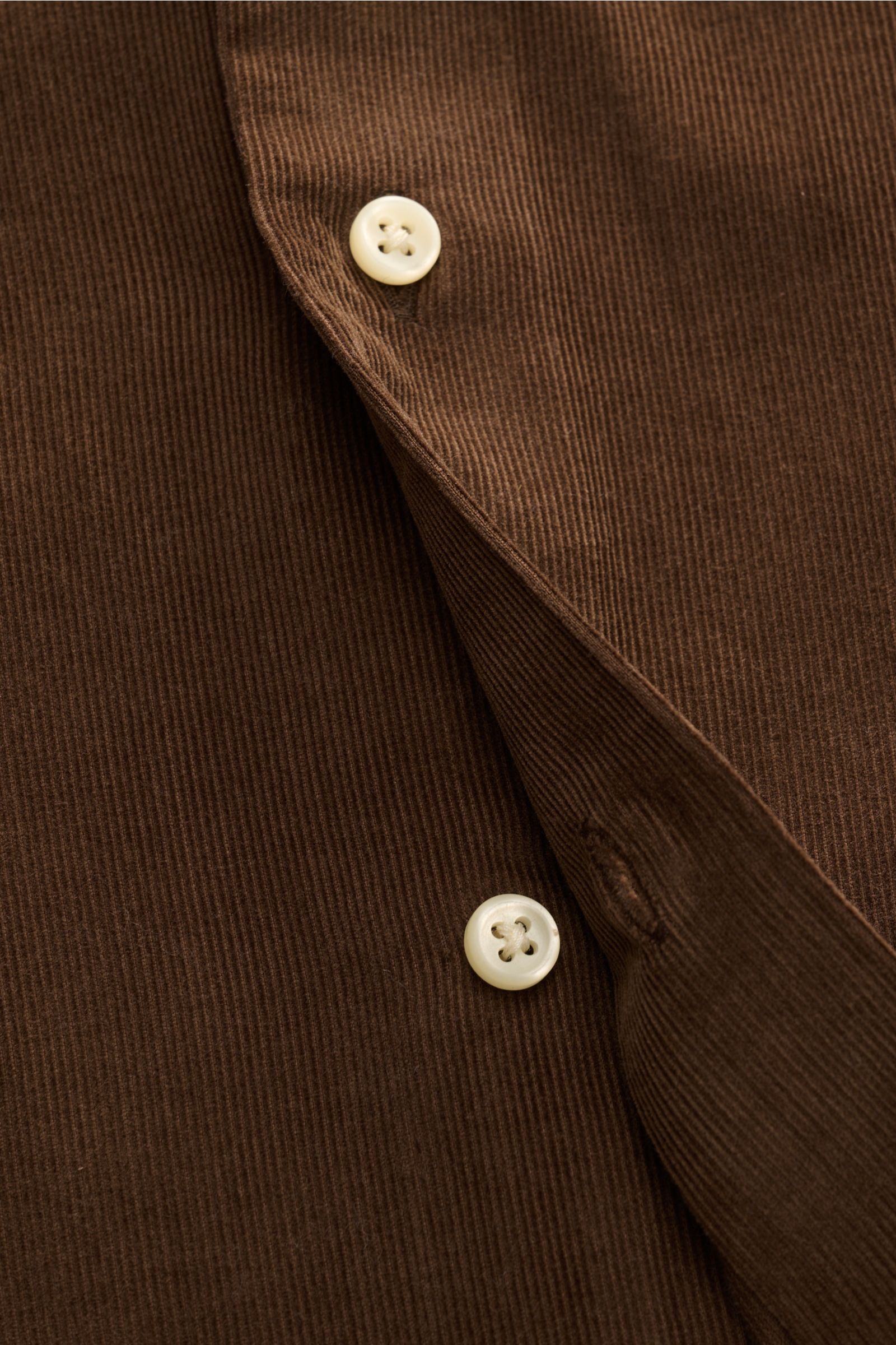 Nahaufnahme eines braunen Polo Ralph Lauren Cord-Hemd Haifisch-Kragen braun aus feinem Baumwoll-Cord, mit weißen Knöpfen und sichtbarer Knopfleiste.