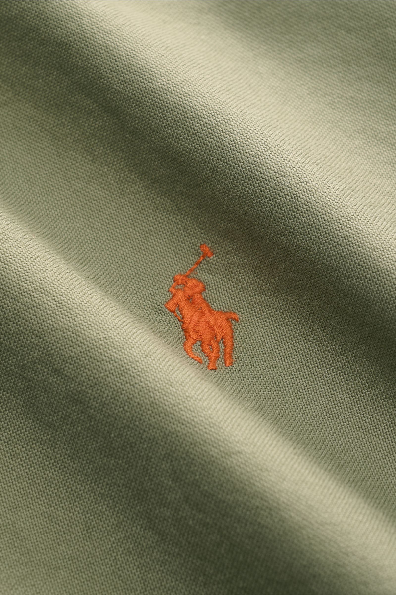 Close-up front view of the Polo Ralph Lauren Oxford-Hemd Button-Down-Kragen graugrün fabric with orange embroidered logo on grey-green cotton textile. Vielseitiger Begleiter für die Herbstsaison: Das POLO RALPH LAUREN Hemd rundet legere Looks mit lässiger