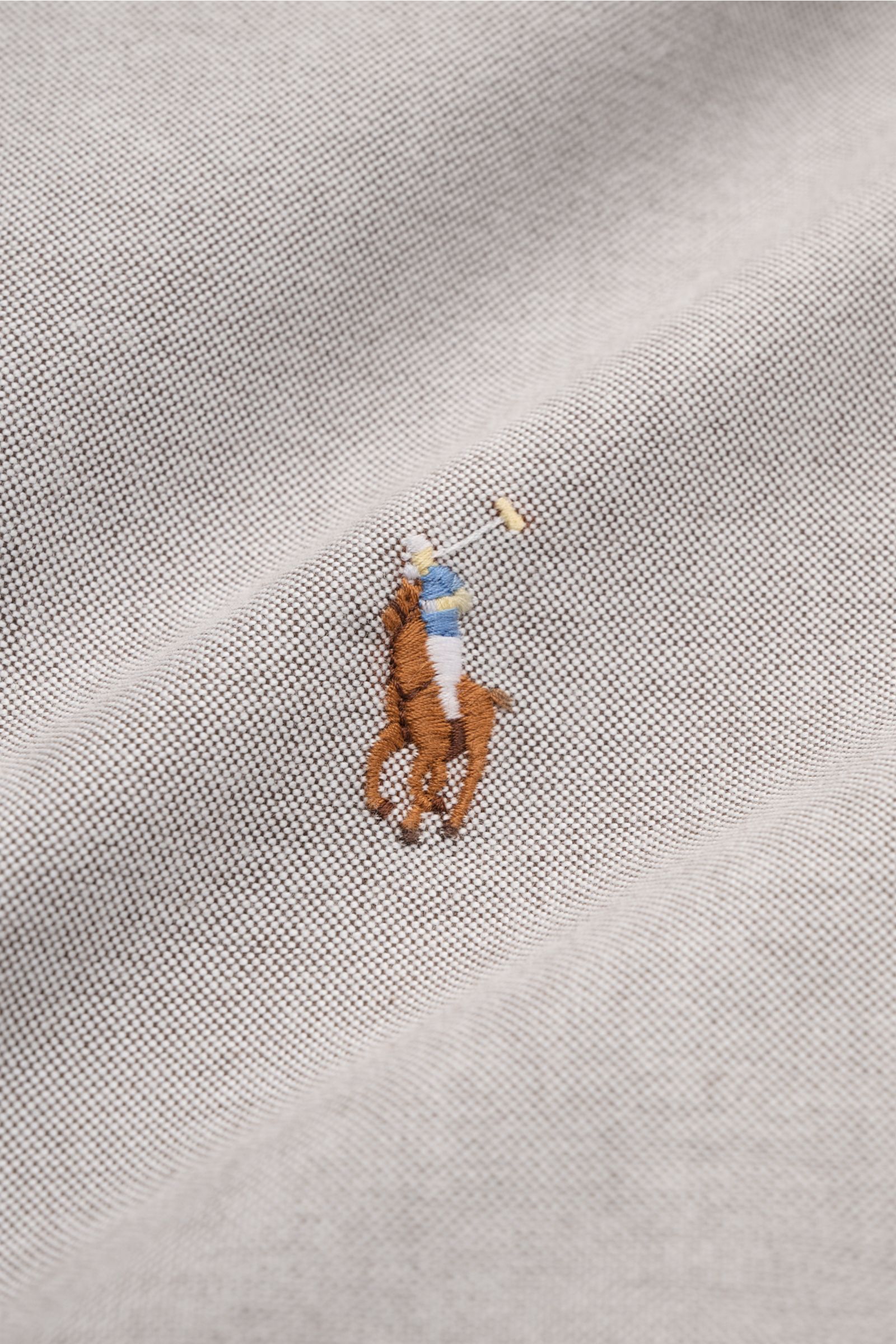 Nahaufnahme des Polo Ralph Lauren Oxford-Hemd Button-Down-Kragen grau mit mehrfarbigem Polospieler-Stitching auf fein strukturiertem Baumwollstoff.