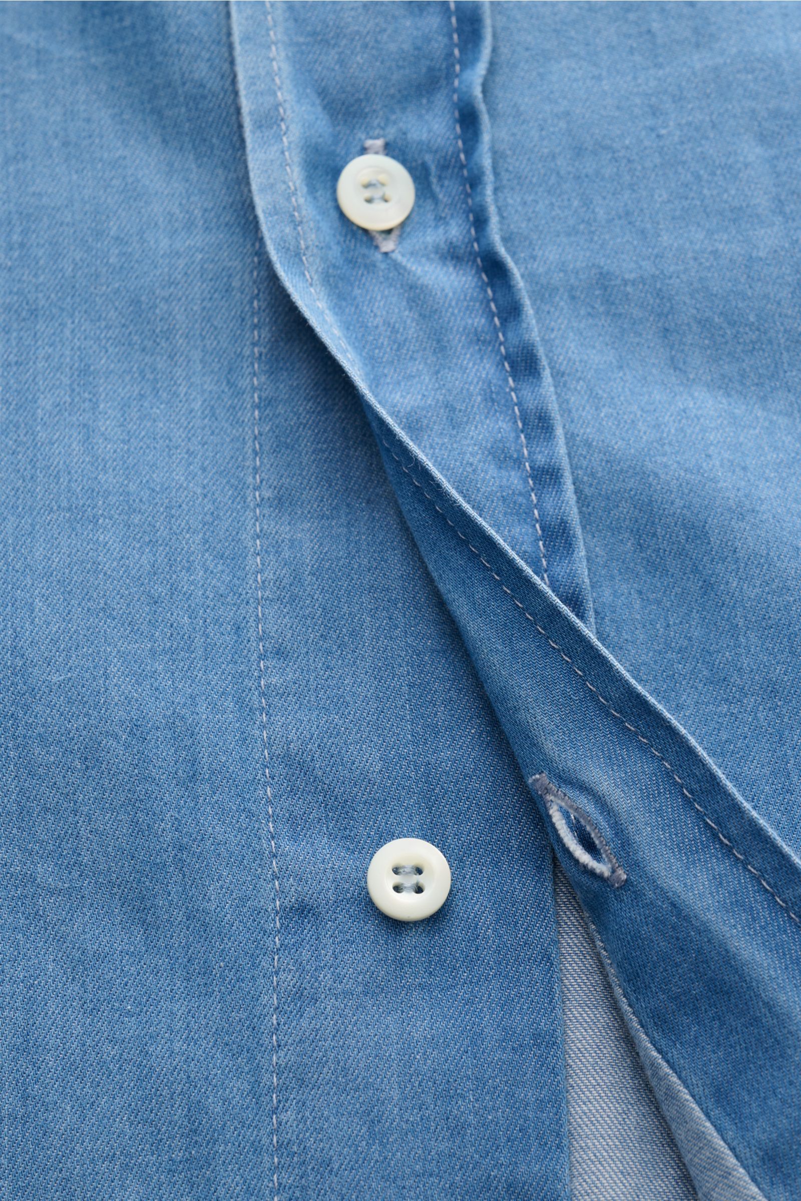 Close-up front view of the blue fabric and buttons of the Brunello Cucinelli Casual Hemd Haifisch-Kragen rauchblau, featuring fine cotton twill with a soft touch in denim look. Dieses Casual Hemd aus reiner, softer Baumwolle von BRUNELLO CUCINELLI ist 