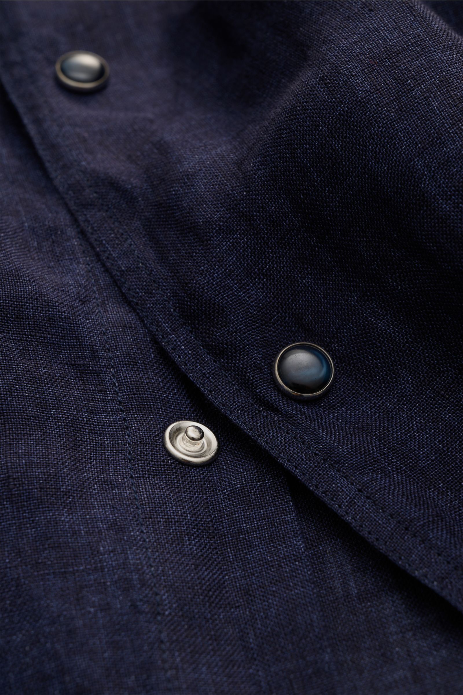 Close-up of Ace Denim Linen shirt shark collar navy fabric and snap buttons, photographed from a top angle showing texture and stitching. Stay comfortable in the warmer months: This ACE DENIM shirt in lightweight linen fabric is a casual statement piece f