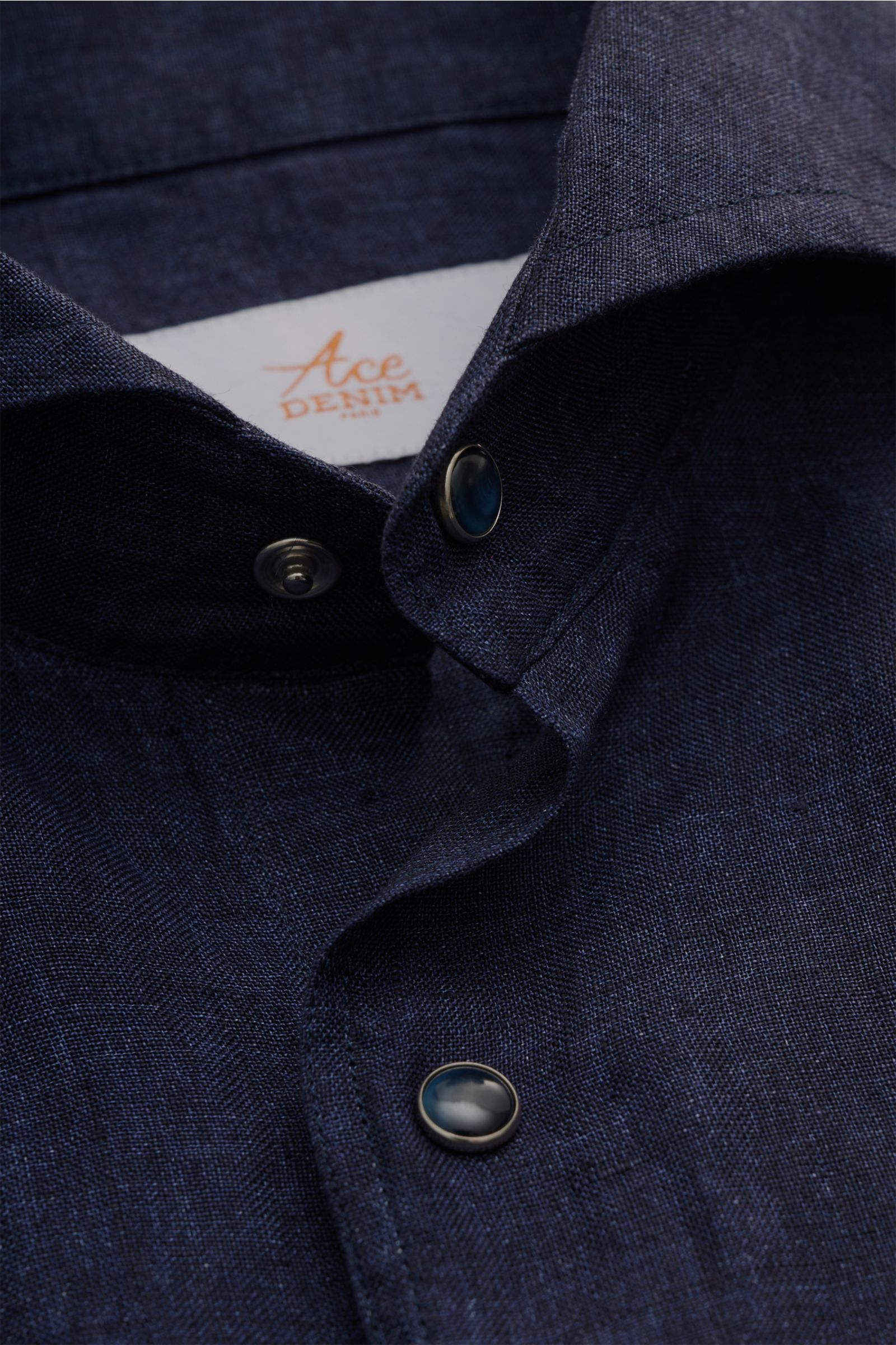 Close-up view of the Ace Denim Linen shirt shark collar navy, showing the textured navy linen fabric and snap buttons on the collar and placket from a top-front perspective. Stay comfortable in the warmer months: This ACE DENIM shirt in lightweight lin