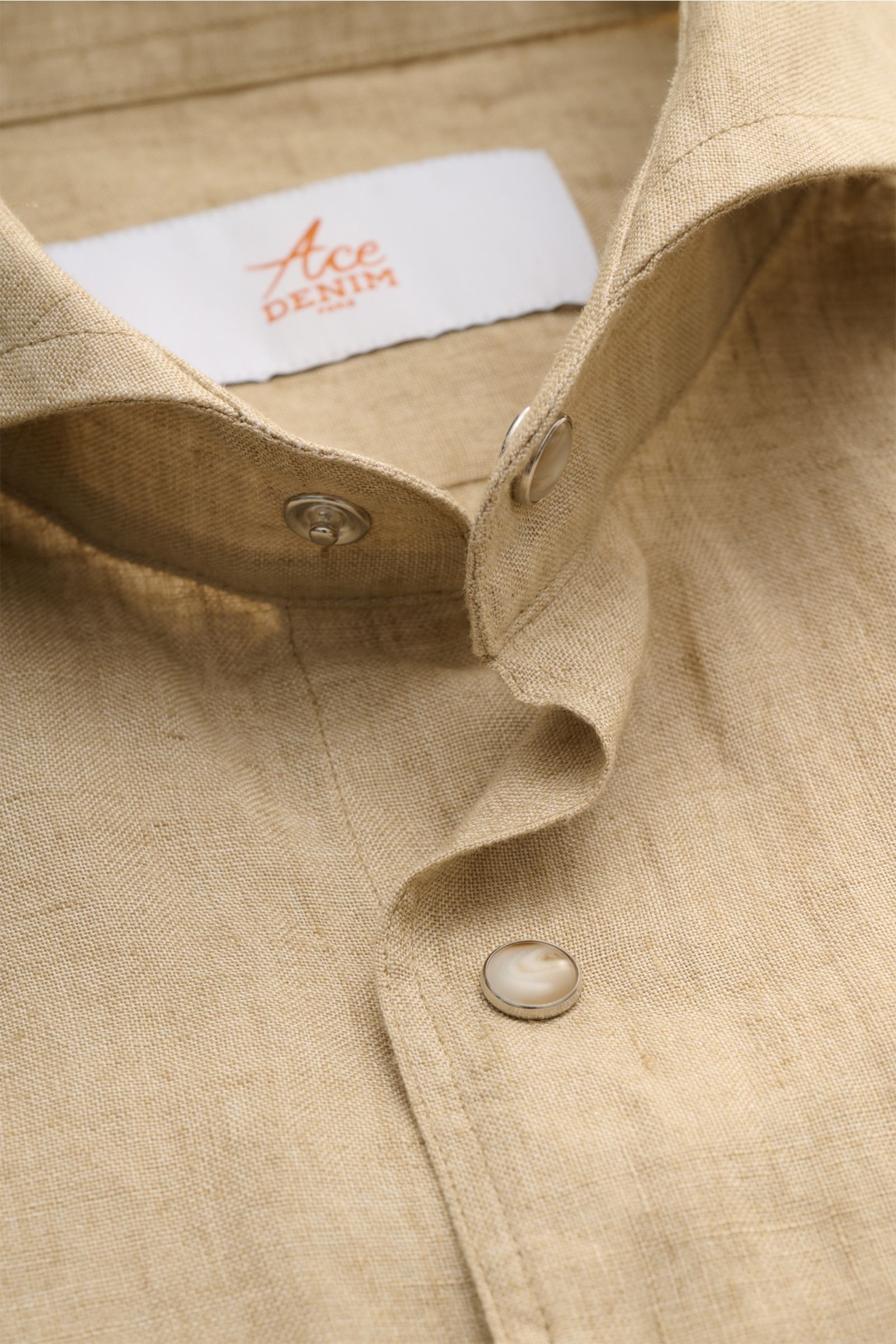 Close-up front view of Ace Denim Linen shirt shark collar beige showing lightweight pure linen fabric, snap buttons, and detailed stitching.

Stay comfortable in the warmer months: This ACE DENIM shirt in lightweight linen fabric is a casual statement 