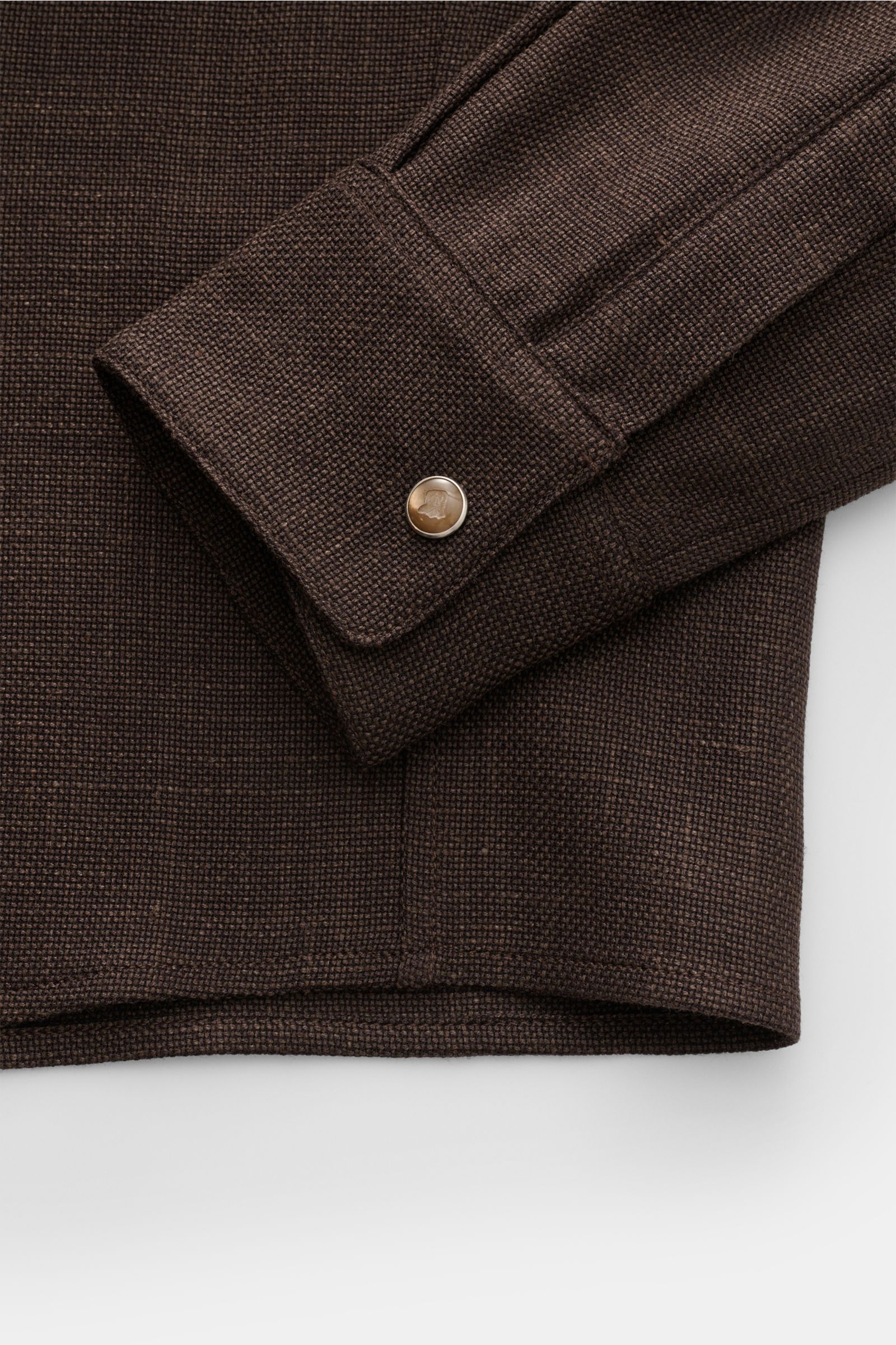 Close-up front view of the Marco Pescarolo Casual Hemd 'Next' Kent-Kragen dunkelbraun showing the dark brown slim fit shirt cuff with elegant button, made of a wool, linen, and silk mix with airy Panama weave.

Description: 
Eleganter Freizeitlook mit 