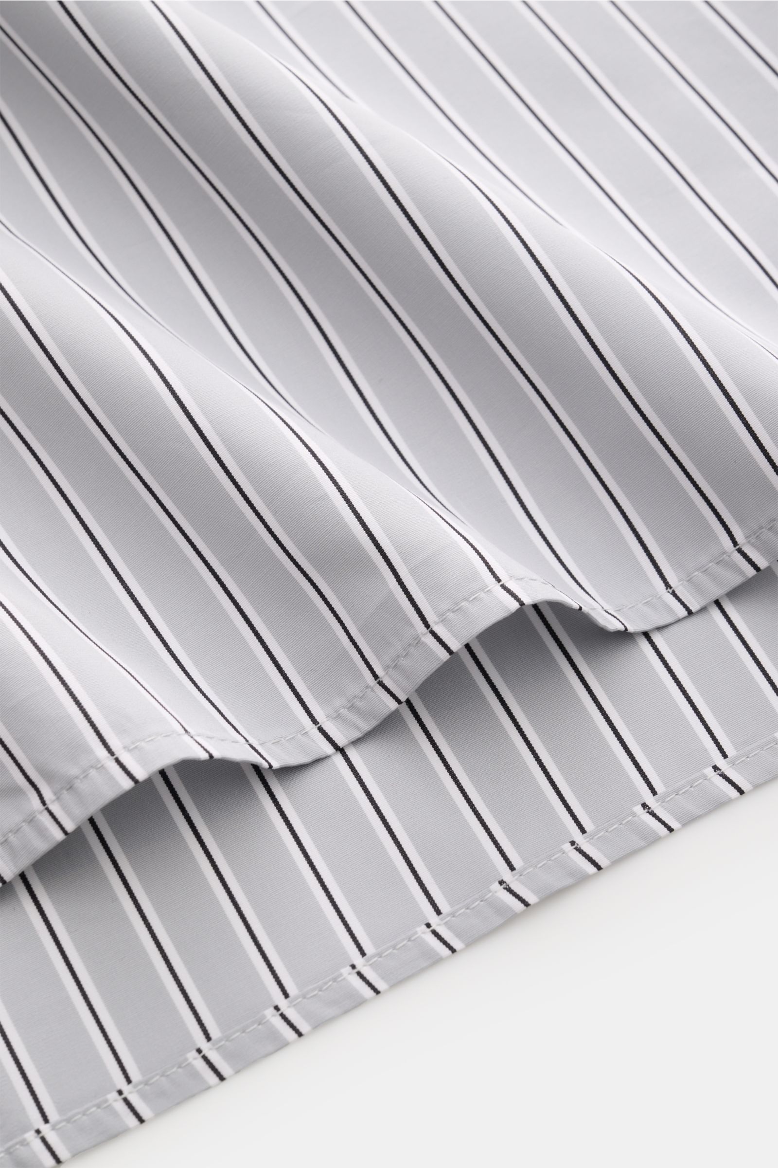 Nahaufnahme des Saumverlaufs des A.P.C. Casual Hemd Kent-Kragen hellgrau/schwarz/weiß gestreift aus glatter Baumwolle im oversized Fit.