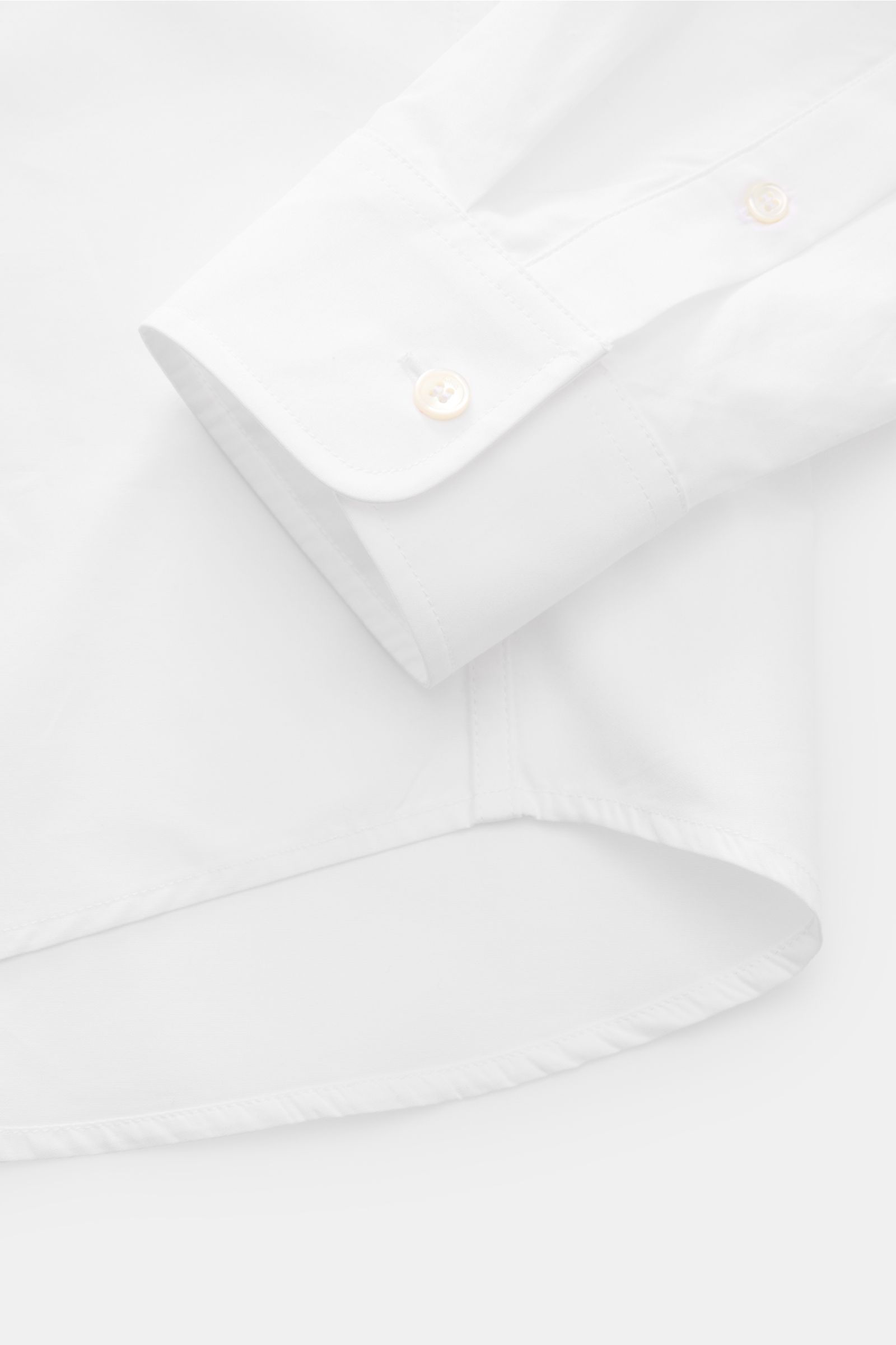 Close-up side view of A.P.C. Casual shirt Kent collar white showing smooth pure cotton fabric, oversized fit, Kent collar, patch button placket, barrel cuffs, patch breast pocket, and slightly rounded hem.