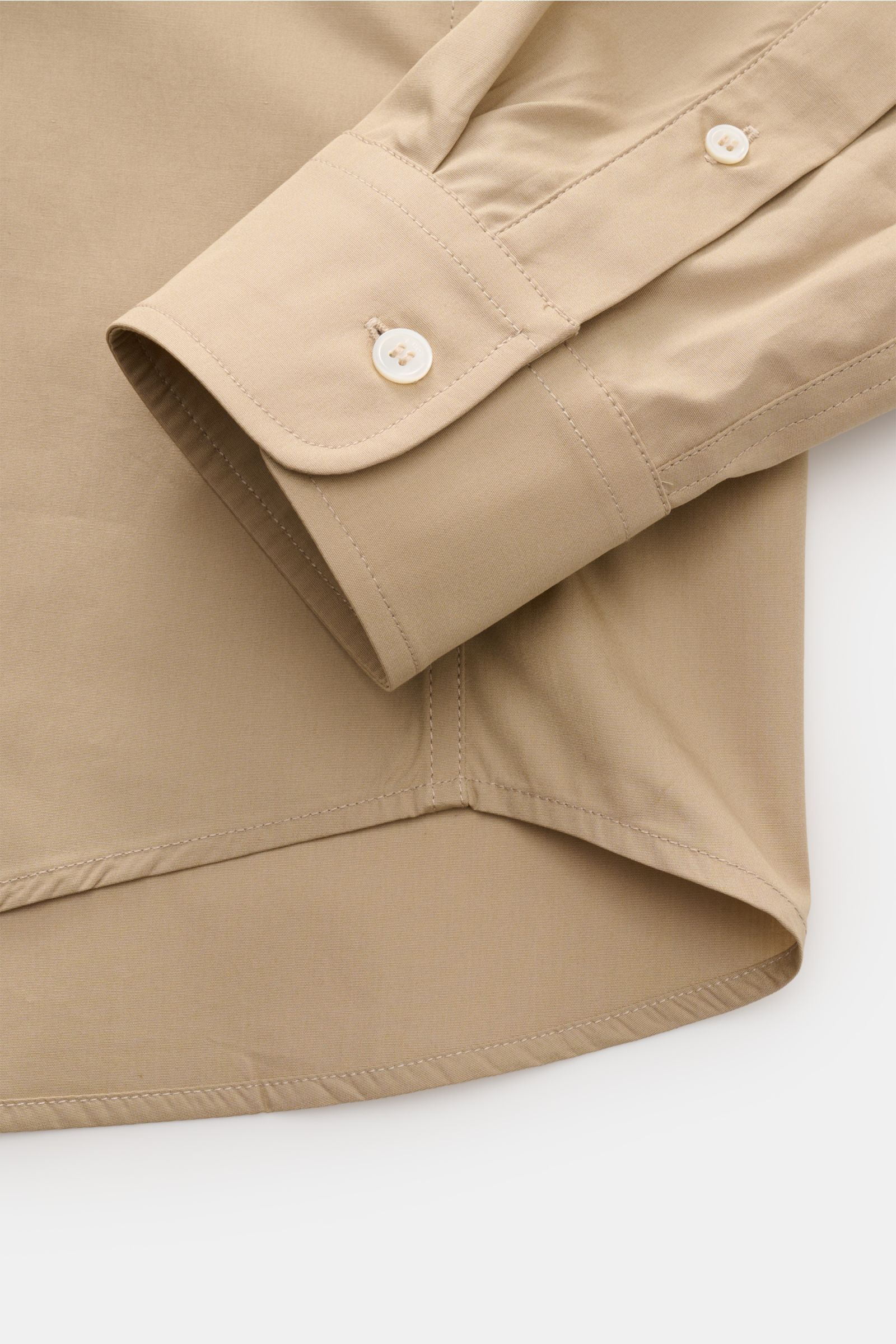 Close-up from above of the cuff and rounded hem of the A.P.C. Casual shirt Kent collar sand, showing smooth pure cotton fabric and buttons.
