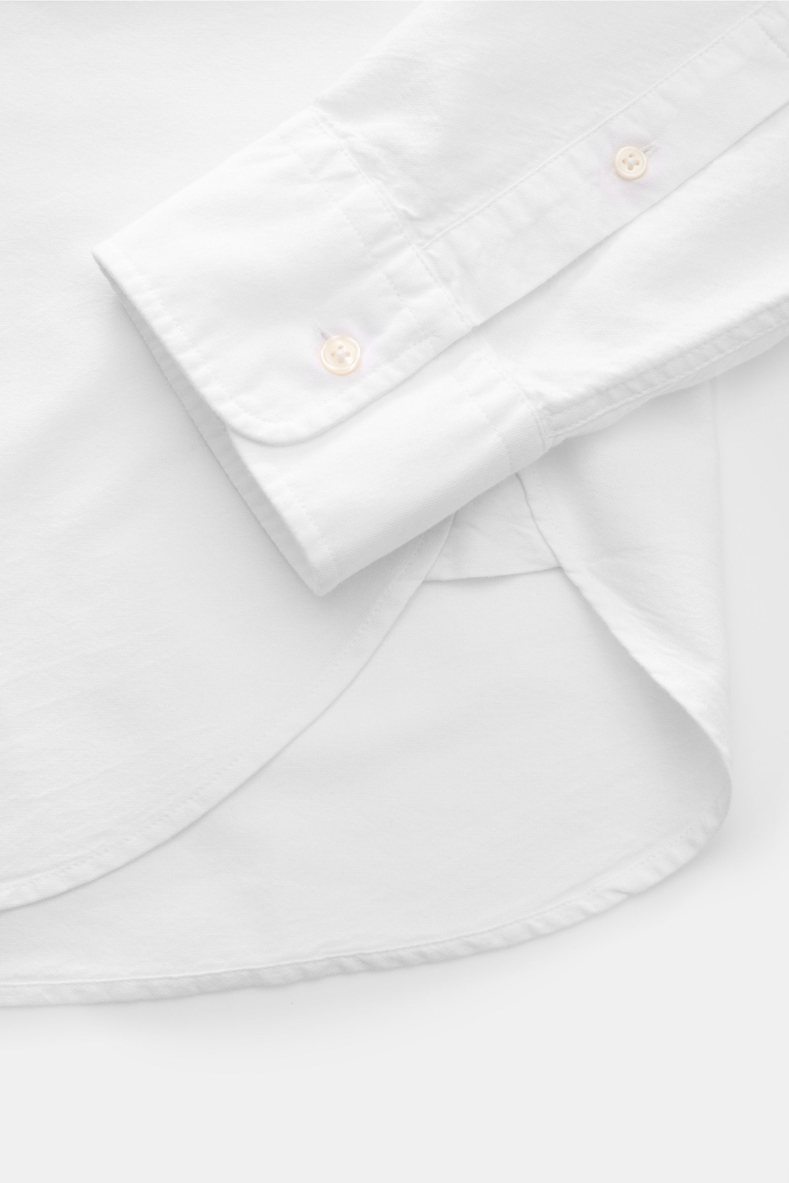 Officine Générale Oxford-Hemd Button-Down-Kragen weiß shown from a close-up top-side view, highlighting the soft cotton cuff, button placket, and slightly rounded hem.

Zeitloses Essential: Das Oxford-Hemd von OFFICINE GÉNÉRALE überzeugt mit seinem kla