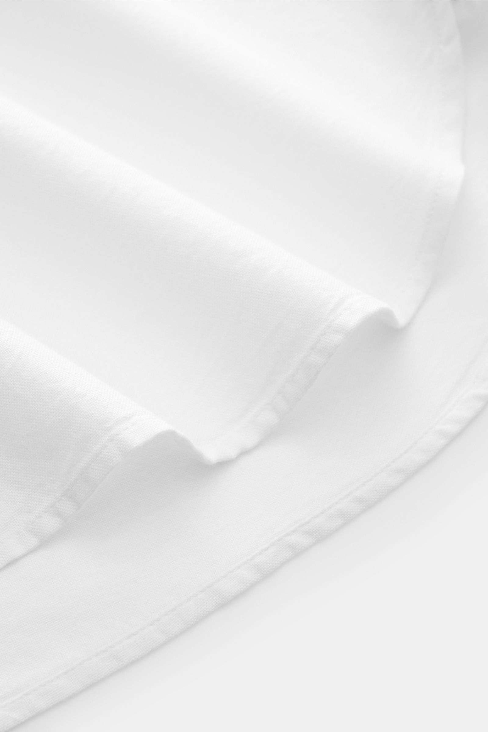 Close-up side view of Officine Générale Oxford-Hemd Button-Down-Kragen weiß showing soft cotton fabric, regular fit, button-down collar, and rounded hem.

Zeitloses Essential: Das Oxford-Hemd von OFFICINE GÉNÉRALE überzeugt mit seinem klassischen Desig