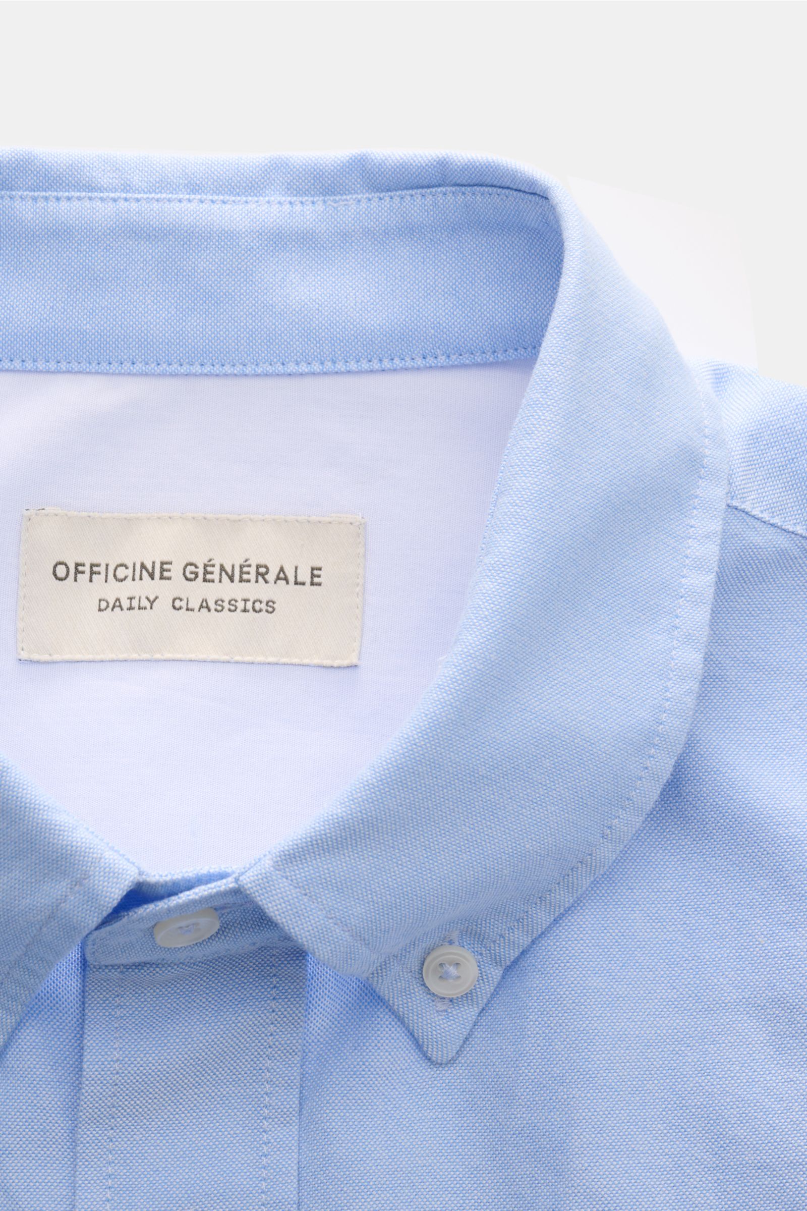 Close-up front view of Officine Générale Oxford-Hemd Button-Down-Kragen hellblau in soft light blue cotton with button-down collar, classic button placket, and fabric label inside collar.

Zeitloses Essential: Das Oxford-Hemd von OFFICINE GÉNÉRALE über