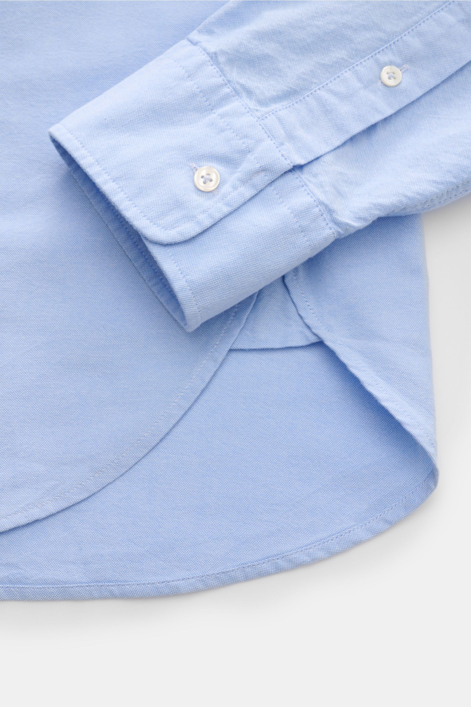 Close-up side view of Officine Générale Oxford-Hemd Button-Down-Kragen hellblau showing light blue cotton fabric, buttoned cuff, and curved hem.

Zeitloses Essential: Das Oxford-Hemd von OFFICINE GÉNÉRALE überzeugt mit seinem klassischen Design und wir