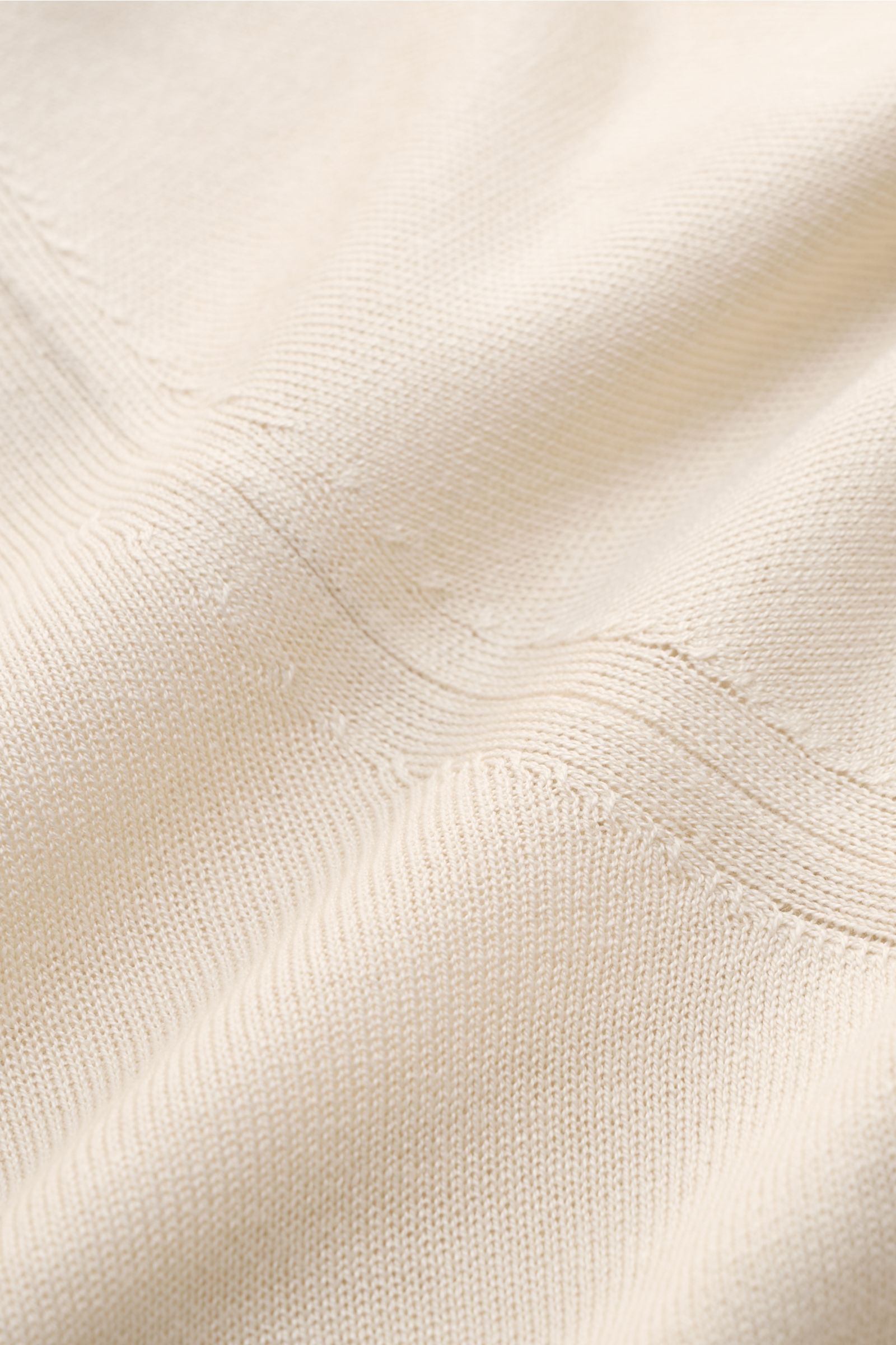 Nahaufnahme des luftigen, feinen Strickbildes eines cremefarbenen Lardini Seiden-Strickhemds mit weichem Griff, aus schräger Perspektive.
