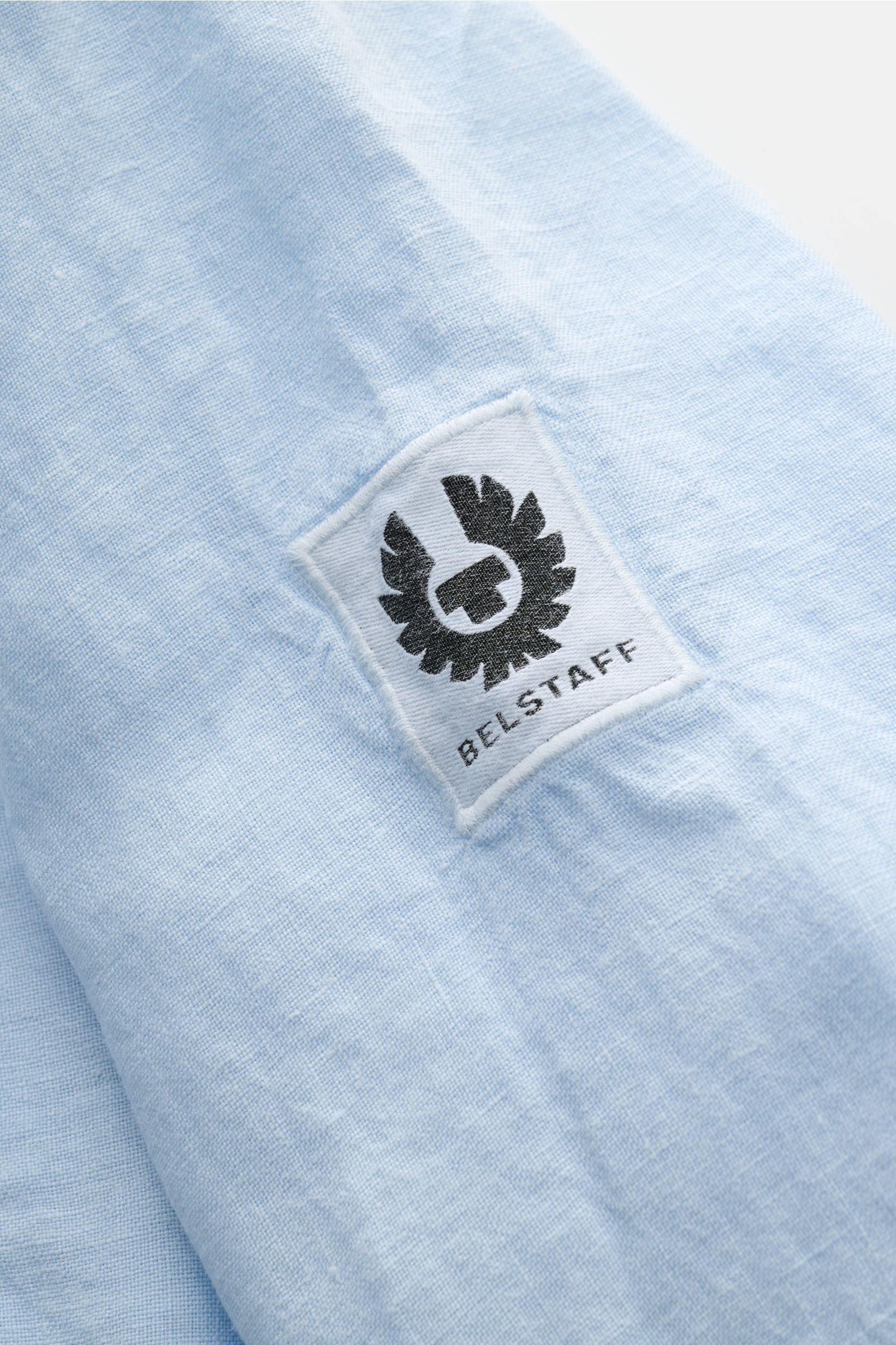 Belstaff Leinenhemd schmaler Kragen hellblau, Detailaufnahme des BELSTAFF-Weblabels auf weichem, reinem Leinenstoff aus schräger Perspektive.