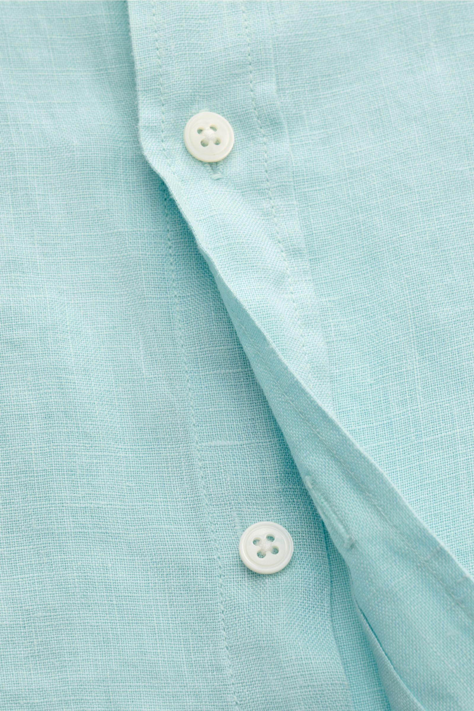 Close-up front view of the button placket on the 04651/ A trip in a bag Leinenhemd Kent-Kragen türkis, made of soft pure linen with an oversized fit. Ideal für die Übergangszeit: Das Leinenhemd von 04651/ A TRIP IN A BAG vereint stilvolle Leichtigkeit mit