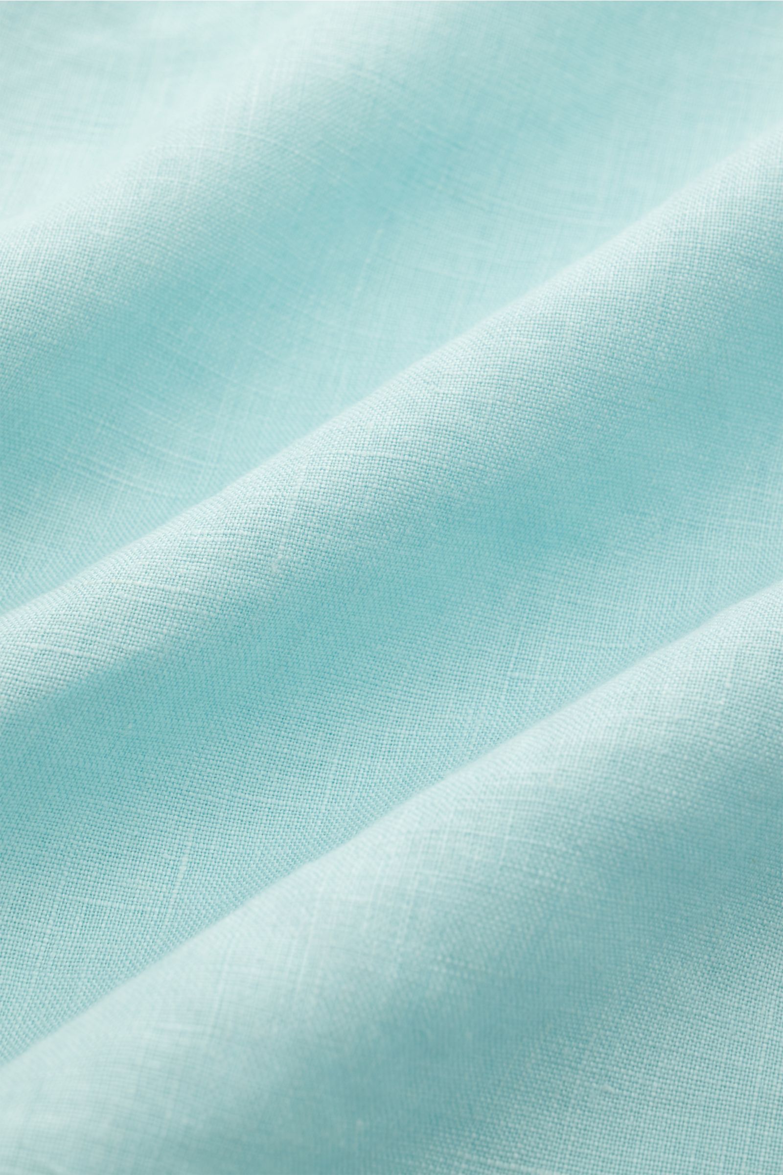 Close-up of soft turquoise linen fabric showing fine texture and weave, highlighting material for 04651/ A trip in a bag Leinenhemd Kent-Kragen türkis, ideal for transitional seasons with pure linen, soft feel, oversized fit, Kent collar, sewn button plac