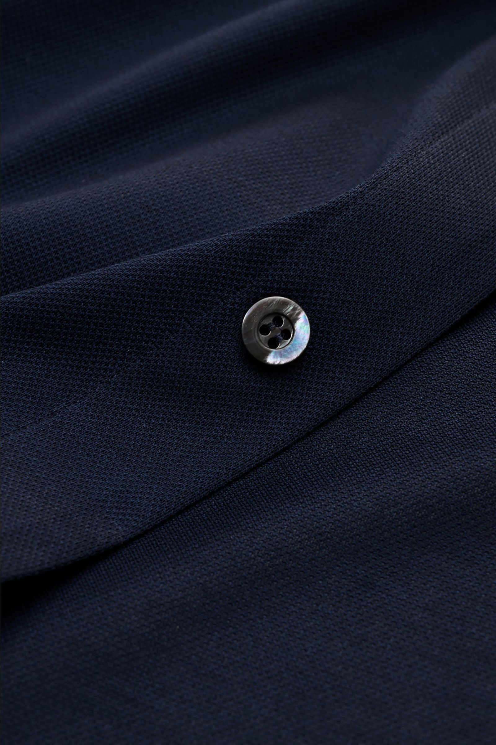 Close-up front perspective of the Fray Piqué-Hemd Haifisch-Kragen 'Lione Cucitura' navy, showing textured cotton piqué fabric and a button.  
FRAY überzeugt mit dem Hemd 'Lione Cucitura' aus luftigem Piqué, gefertigt aus reiner Baumwolle – ein zeitlose