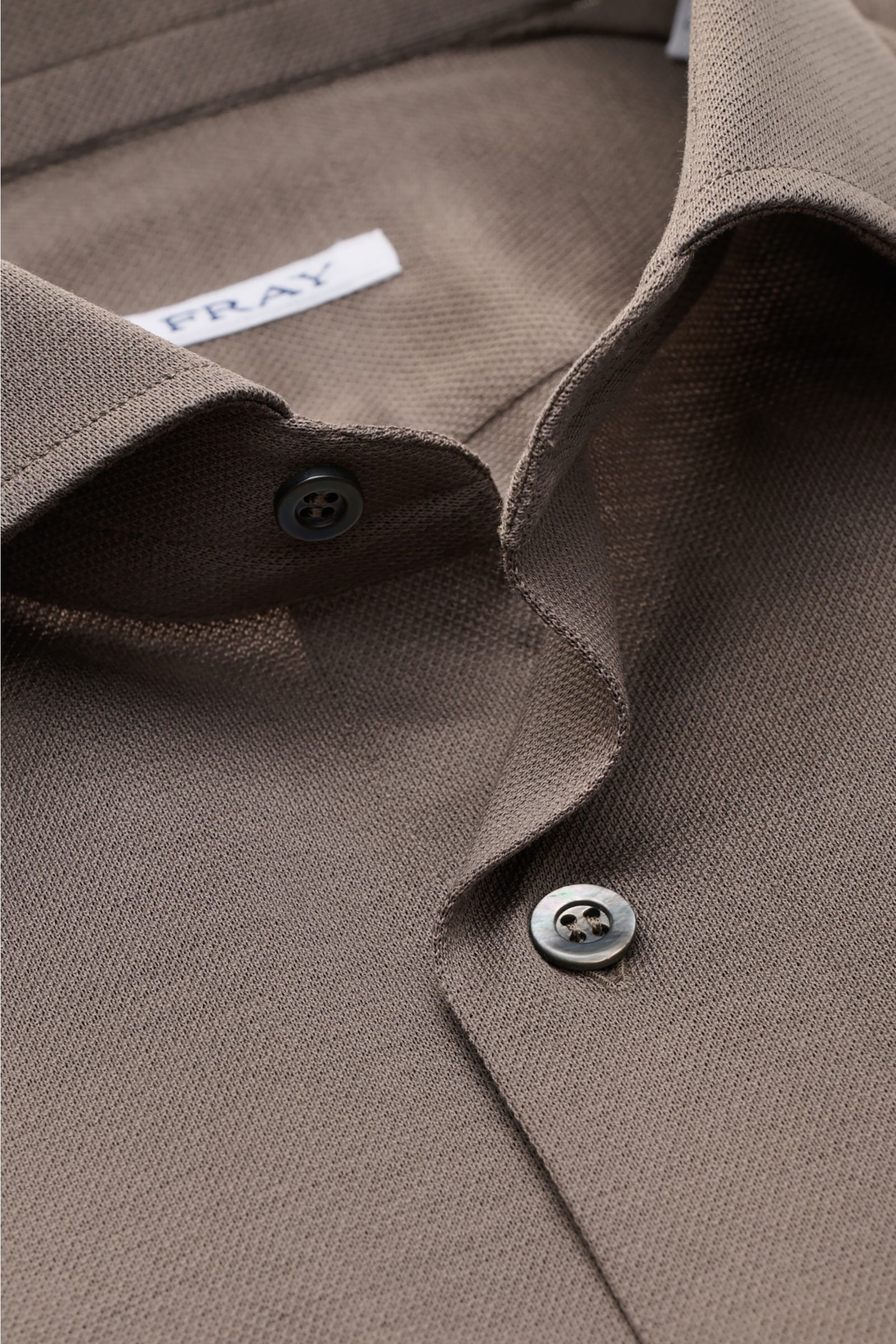 Close-up front view of Fray Piqué-Hemd Haifisch-Kragen 'Lione Cucitura' graubraun in lightweight cotton piqué with shark collar and buttons.

FRAY überzeugt mit dem Hemd 'Lione Cucitura' aus luftigem Piqué, gefertigt aus reiner Baumwolle – ein zeitlose