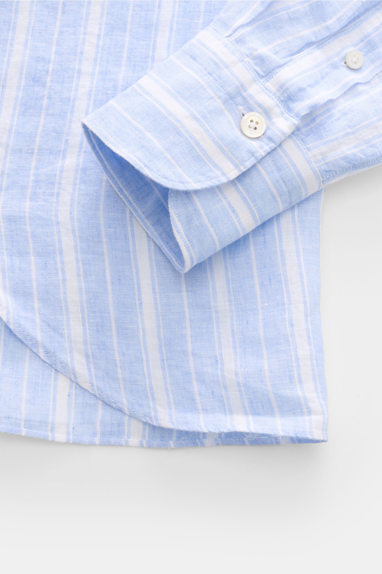 Close-up front side view of Finamore Linen shirt 'Sergio Gaeta' shark collar blue/white striped sleeve cuff with white buttons on lightweight linen fabric.

Stylish summer essential: The lightweight linen shirt 'Sergio Gaeta' by FINAMORE works with a s