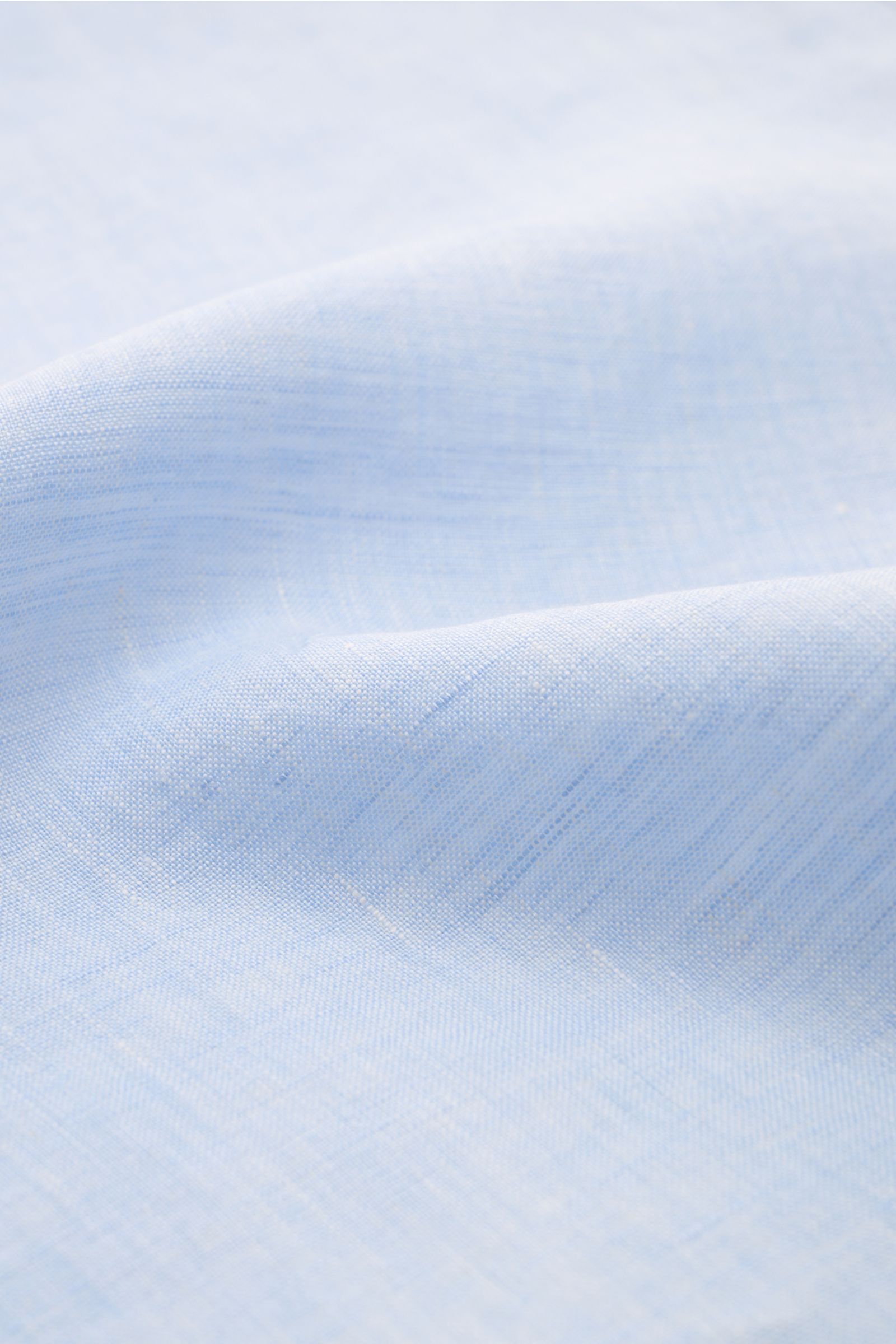 Close-up view of the light blue fabric texture of the Finamore Linen shirt 'Sergio Gaeta' shark collar light blue, showcasing pure linen with a soft feel. Features include regular fit, shark collar, French button placket, classic barrel cuffs, extra-long 