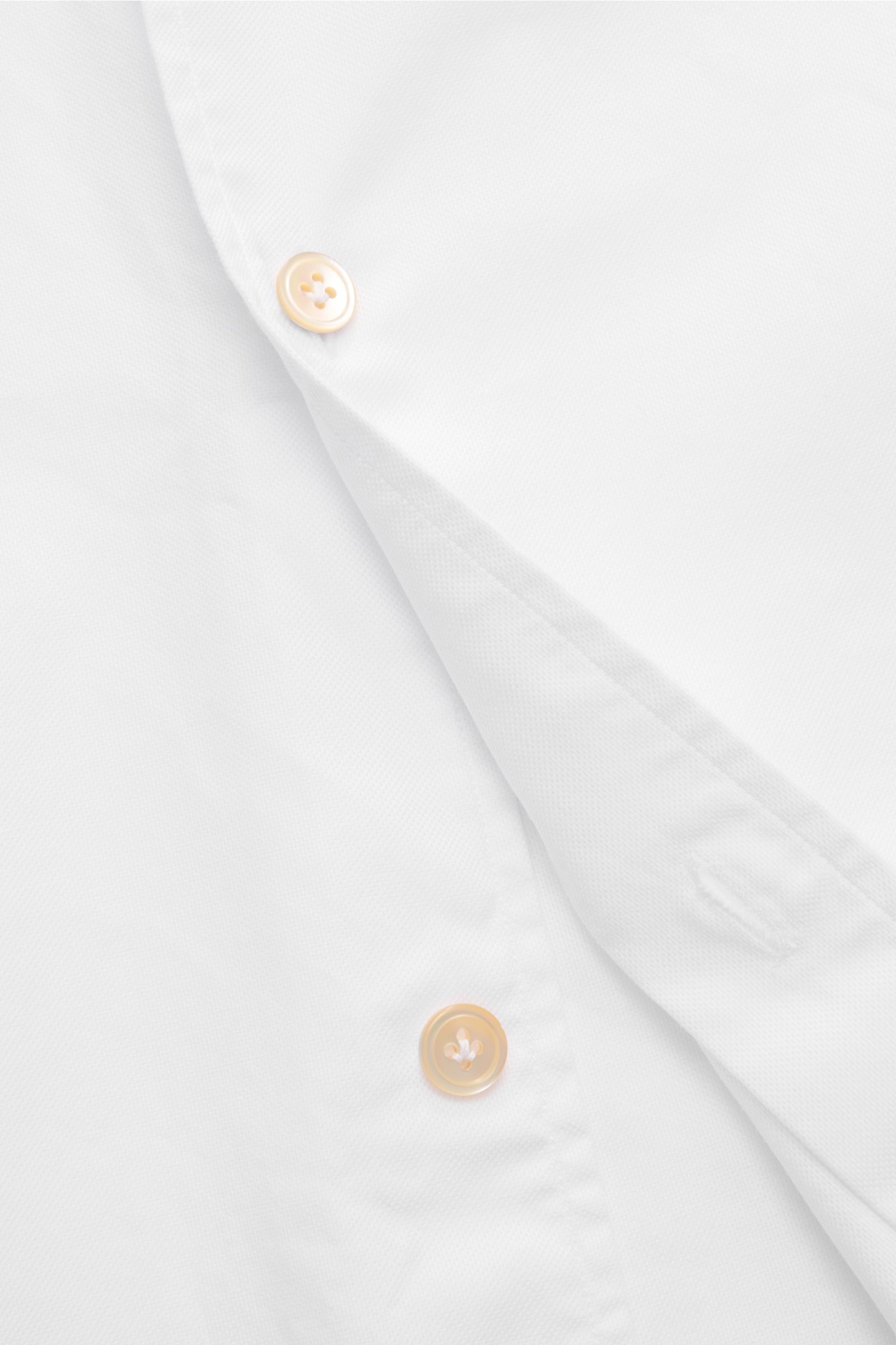 Nahaufnahme des Borrelli Oxford Hemd 'Ettore' Haifisch-Kragen weiß mit Oxford-Baumwollstruktur, französischer Knopfleiste, klassischer Sportmanschette, Extra Slim Fit und gerundetem Saum, fotografiert von oben.