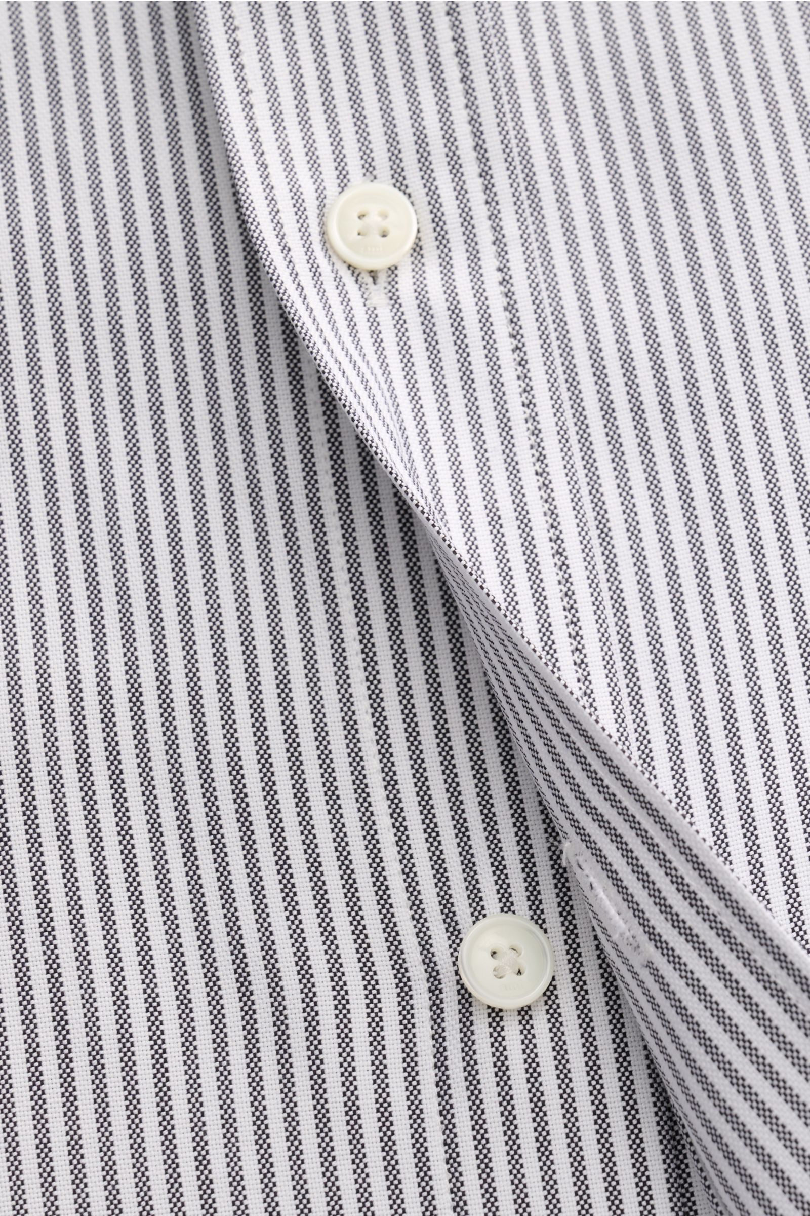 Nahaufnahme aus schräger Perspektive des Ami Paris Oxford-Hemd Button-Down-Kragen anthrazit/weiß gestreift mit Oversized Fit, reiner Baumwolle, klassischem Streifenmuster, aufgesetzter Knopfleiste, markentypischem Bruststick, Sportmanschette und gerundete